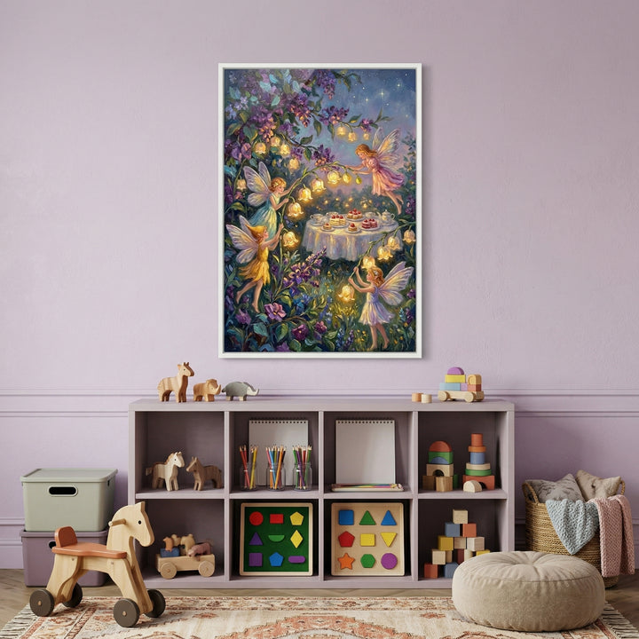 A vertical, rectangular framed piece of art hangs on a soft lavender wall above a child’s storage shelf. The artwork depicts a whimsical scene at night in an enchanted garden. Several small, winged magical beings are gathered around a table covered in a white cloth and topped with various cakes and treats. 