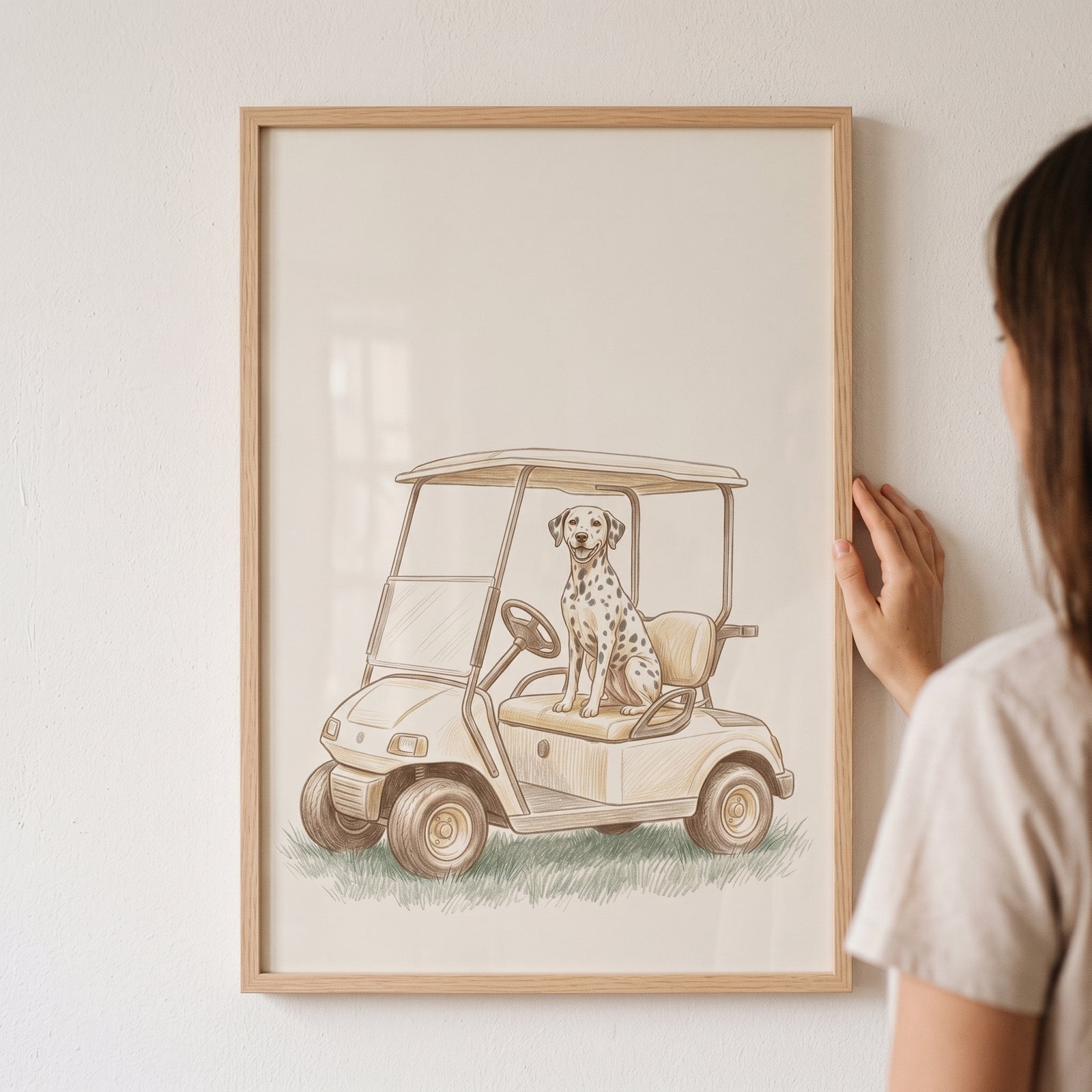 Person holding a framed golf cart sitting dalmatian dog wall art against a white wall.