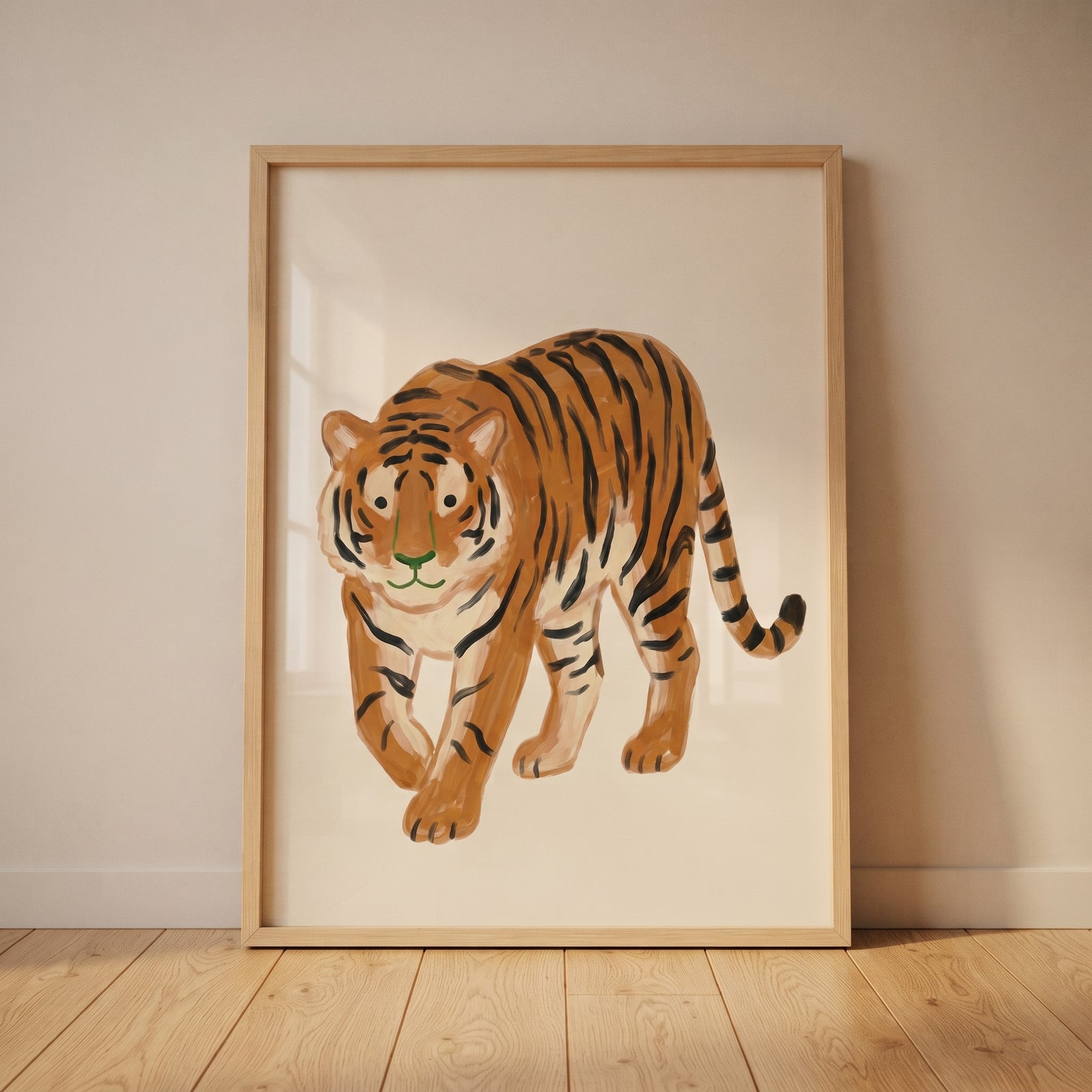 Green nose orange tiger wall art in a light wood frame leaning against a neutral wall on a wooden floor.