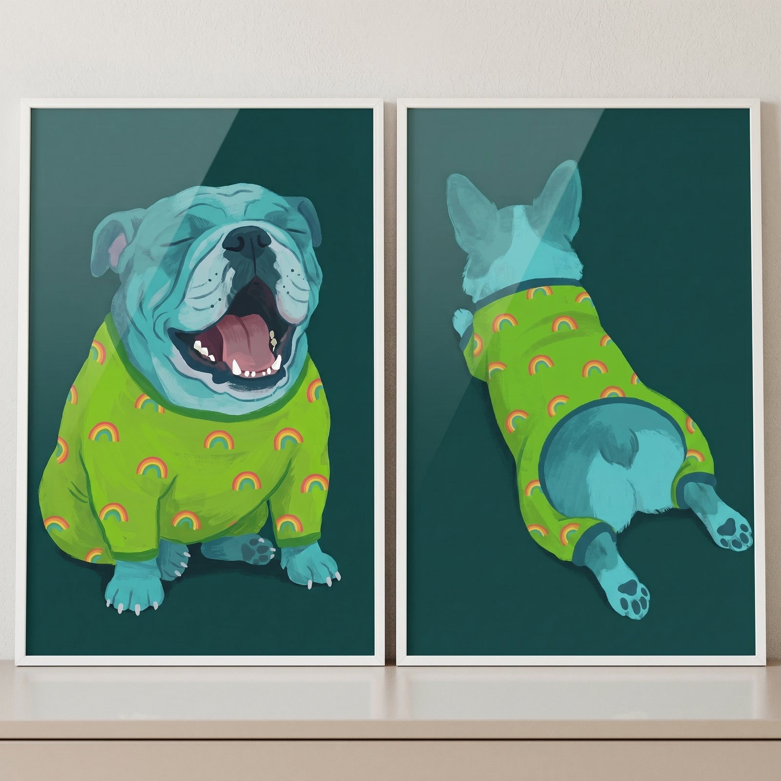 Two framed artworks are displayed side-by-side on a wooden surface. Both feature a teal-colored bulldog in bright green pajamas with a rainbow pattern against a dark green background. The left artwork depicts the dog sitting and yawning widely with its eyes closed.