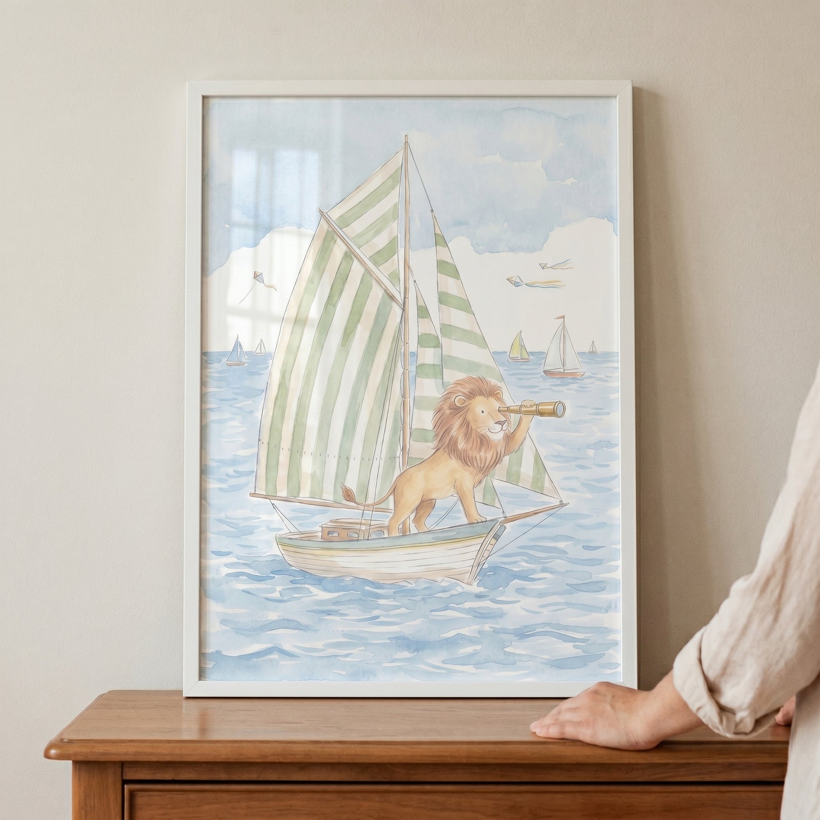 A hand rests near framed green striped sail lion wall art of a lion using a telescope on a sailboat.