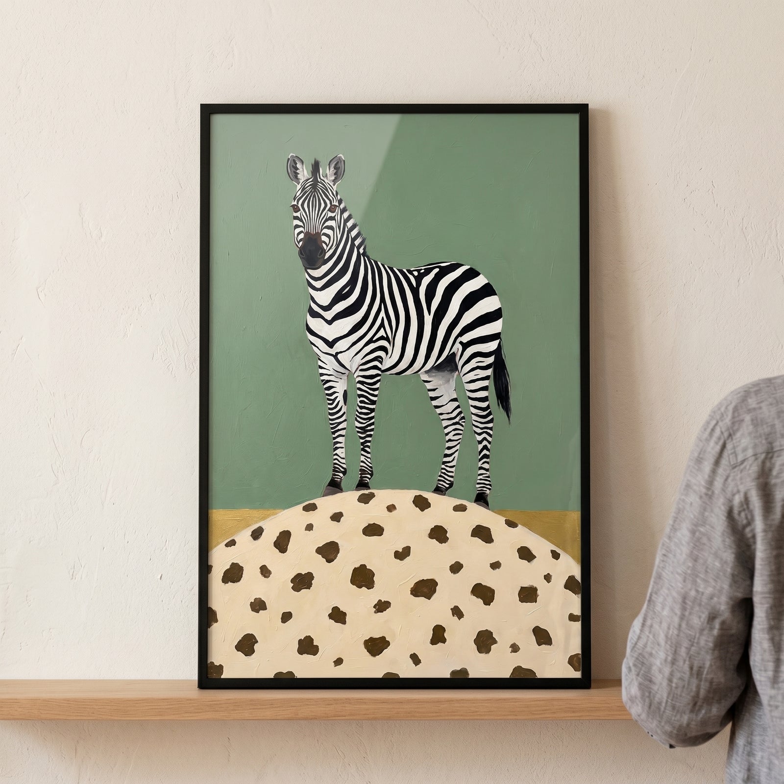 Zebra on a spotted mound with a green textured background zebra wall art in a black frame on a wooden shelf.