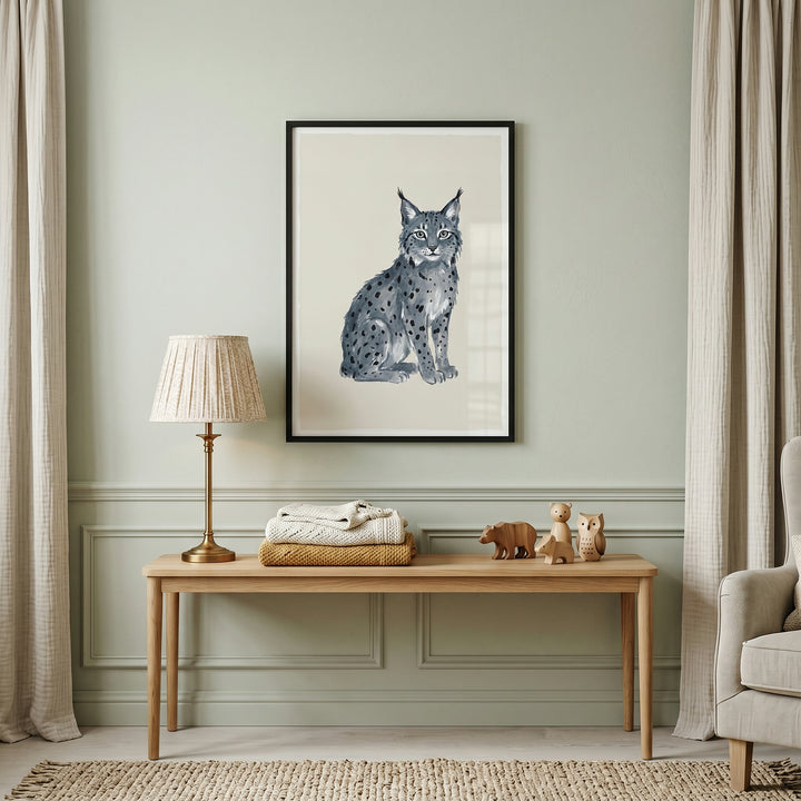Grey tufted ear lynx artwork hangs on a green wall above a wooden bench with a lamp, blankets, and small figurines.