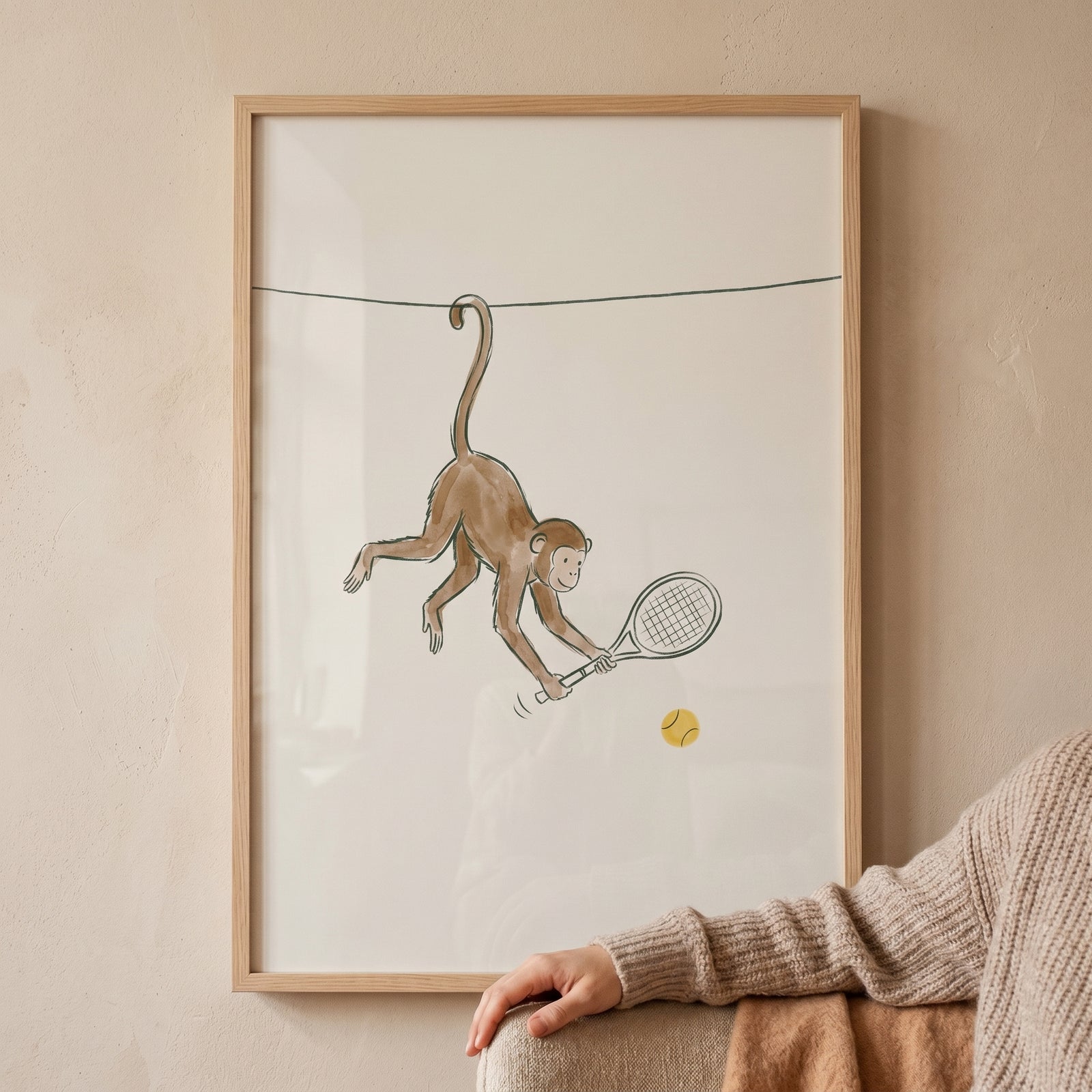 Framed hanging tail tennis monkey wall art showing a brown monkey swinging a racket at a ball while dangling from a wire.