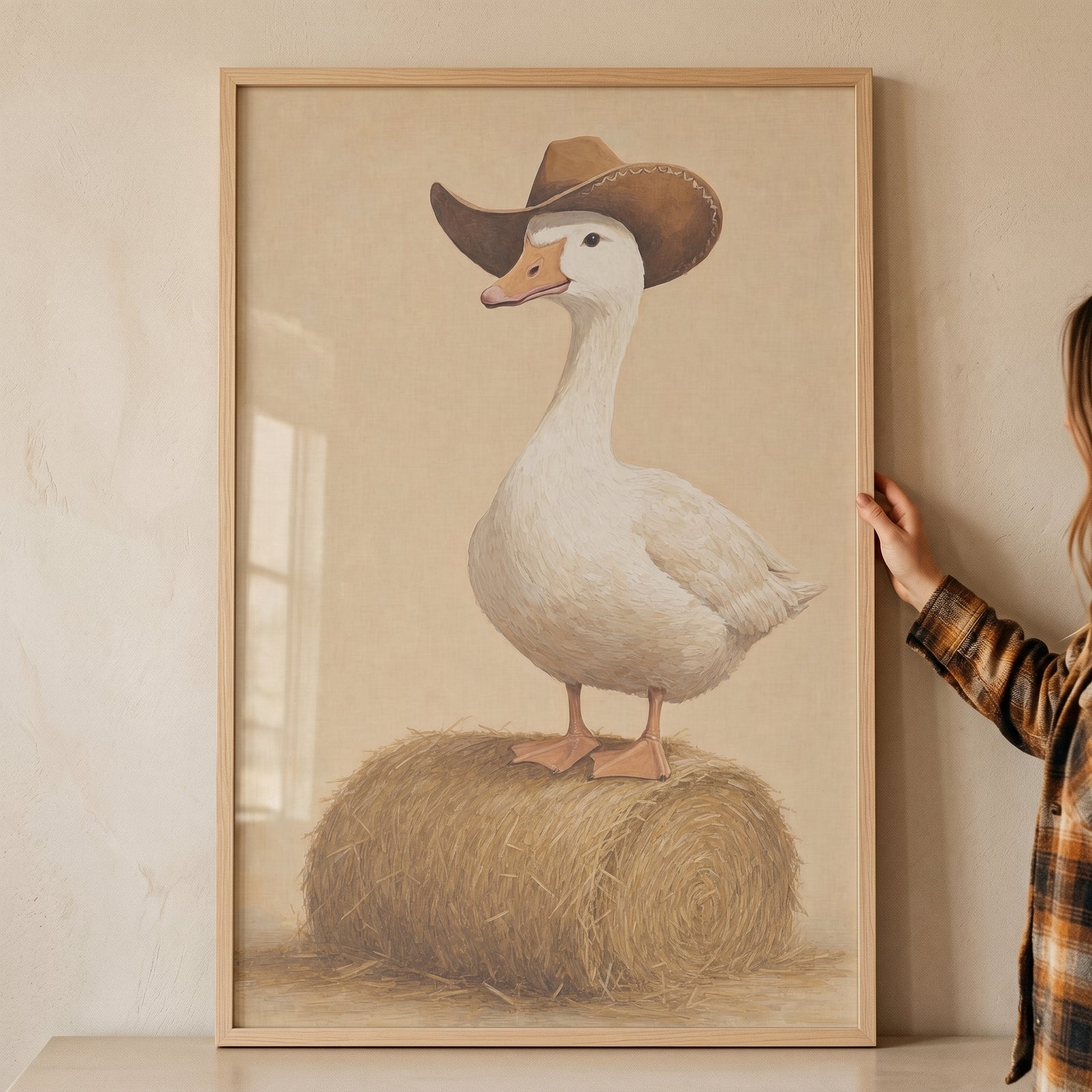 Hay bale standing goose wall art features a white goose in a brown cowboy hat, framed and held against a wall.