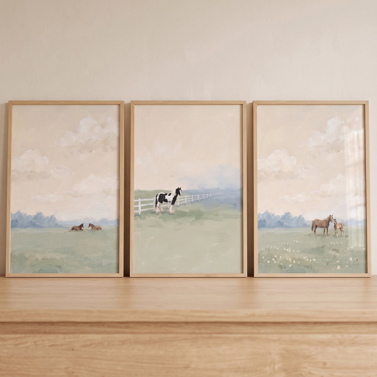 A hazel peach sky horses wall art set of 3 displays equines in a grassy field under a soft, clouded atmosphere.