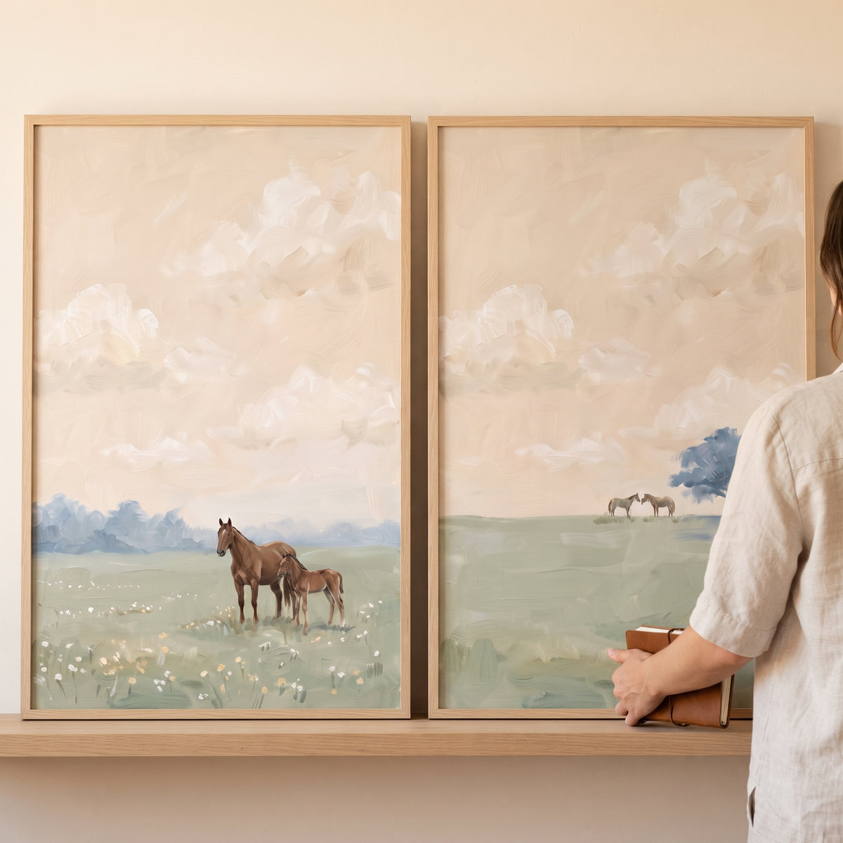 Hazy green field horse wall art set of 2 shows horses and a foal in a meadow under soft skies in light wooden frames.