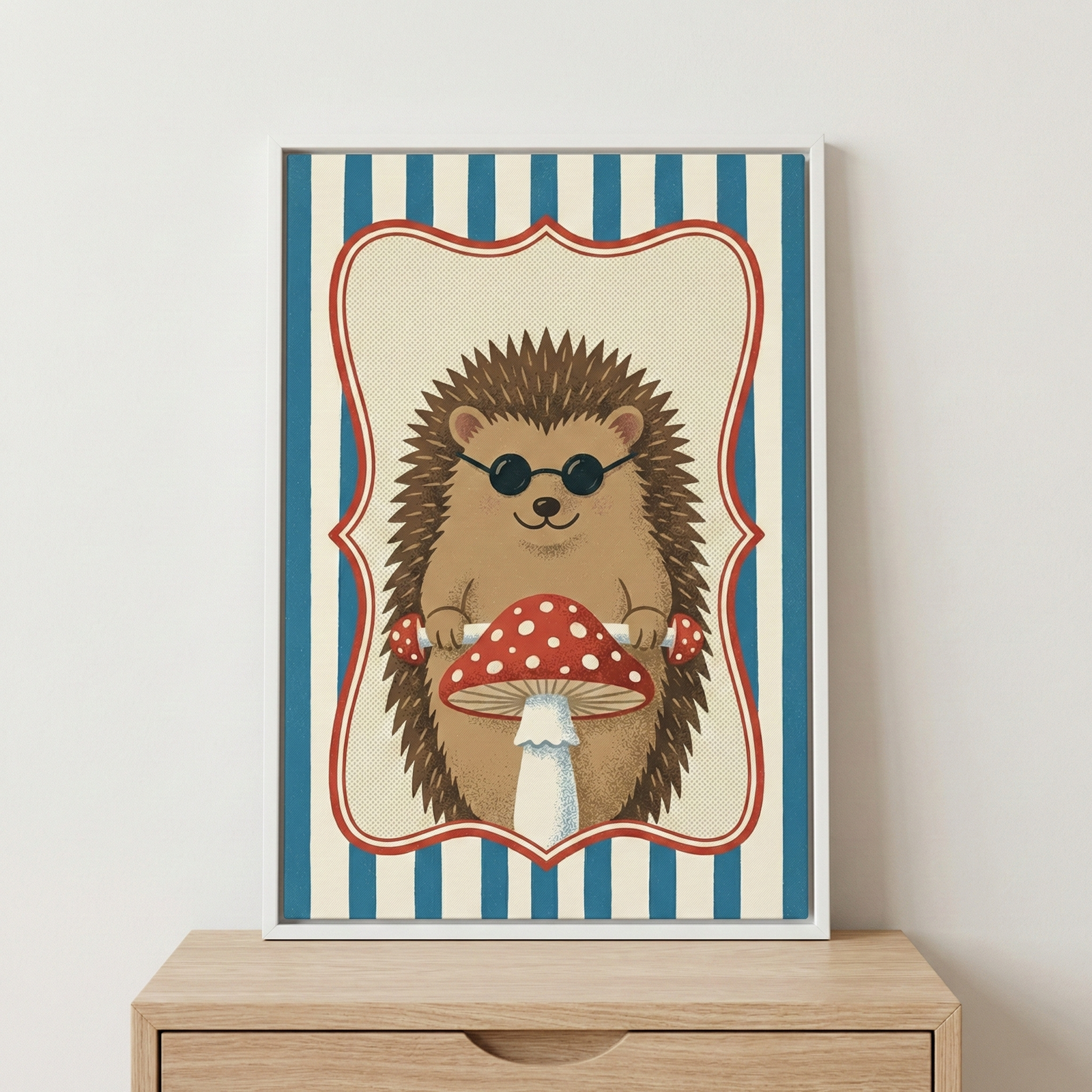 A framed whimsical illustration of a brown hedgehog wearing dark sunglasses. The animal is holding a large red-and-white spotted mushroom. The central image is bordered by a decorative cream-colored frame and set against a backdrop of blue and white vertical stripes. The artwork is housed in a simple white frame, resting on a light-wood chest of drawers against a neutral wall.