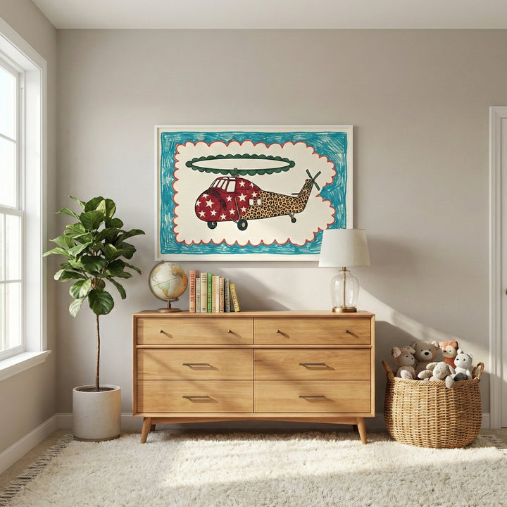 Framed helicopter artwork displayed above a mid-century modern dresser in a softly lit, cozy room with a rug, potted plant, and basket of stuffed animals. The vibrant wall art adds a fun and creative touch to the nursery or kids’ room decor.