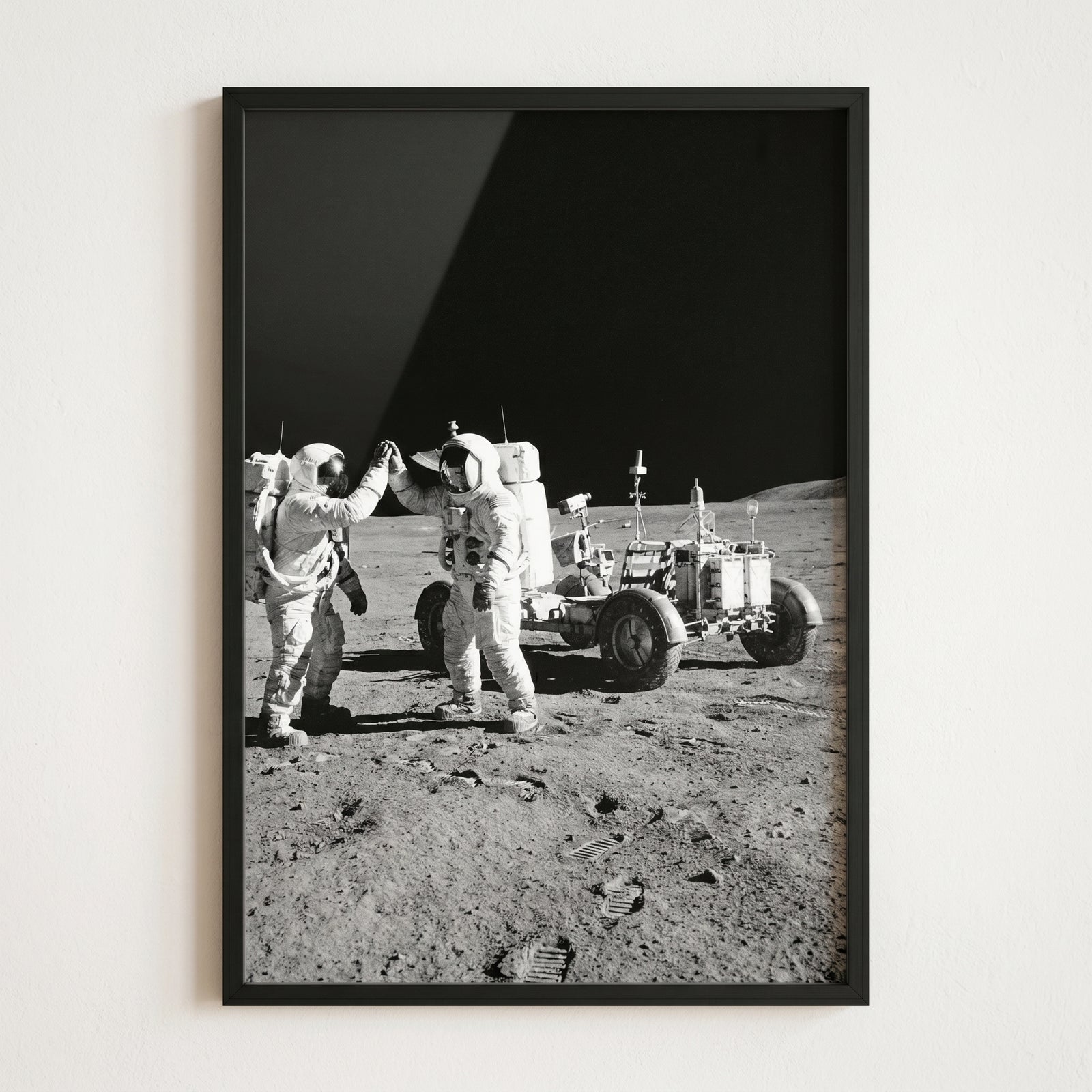 Framed black and white high five moon astronaut wall art of two astronauts celebrating next to a lunar rover.