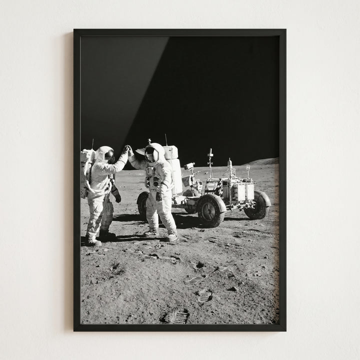 Framed black and white high five moon astronaut wall art of two astronauts celebrating next to a lunar rover.