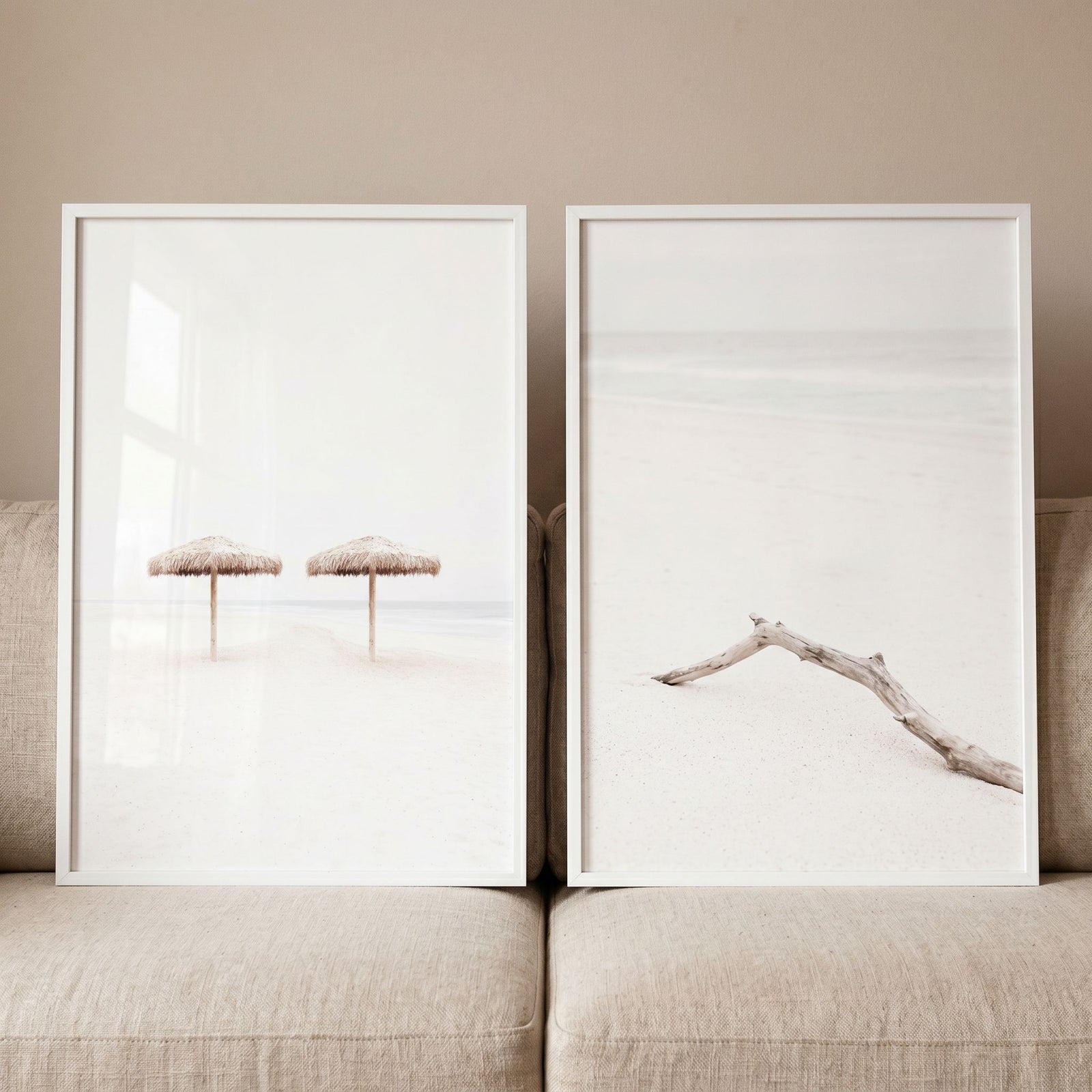 High key neutral beach wall art set of 2 featuring straw umbrellas and driftwood prints leaning against a beige couch.