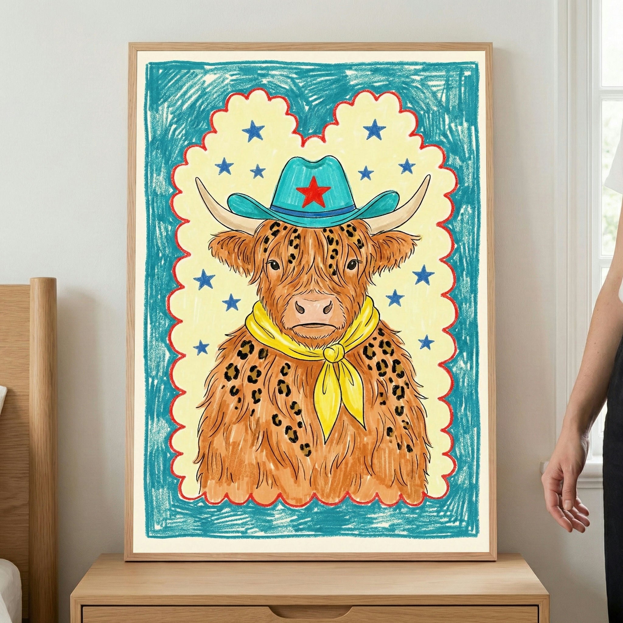 Framed crayon-style illustration of a highland cow with long, shaggy fur wearing a turquoise cowboy hat with a red star and a bright yellow bandana. The playful artwork features a scalloped border and starry background in cheerful blue, yellow, and red tones.