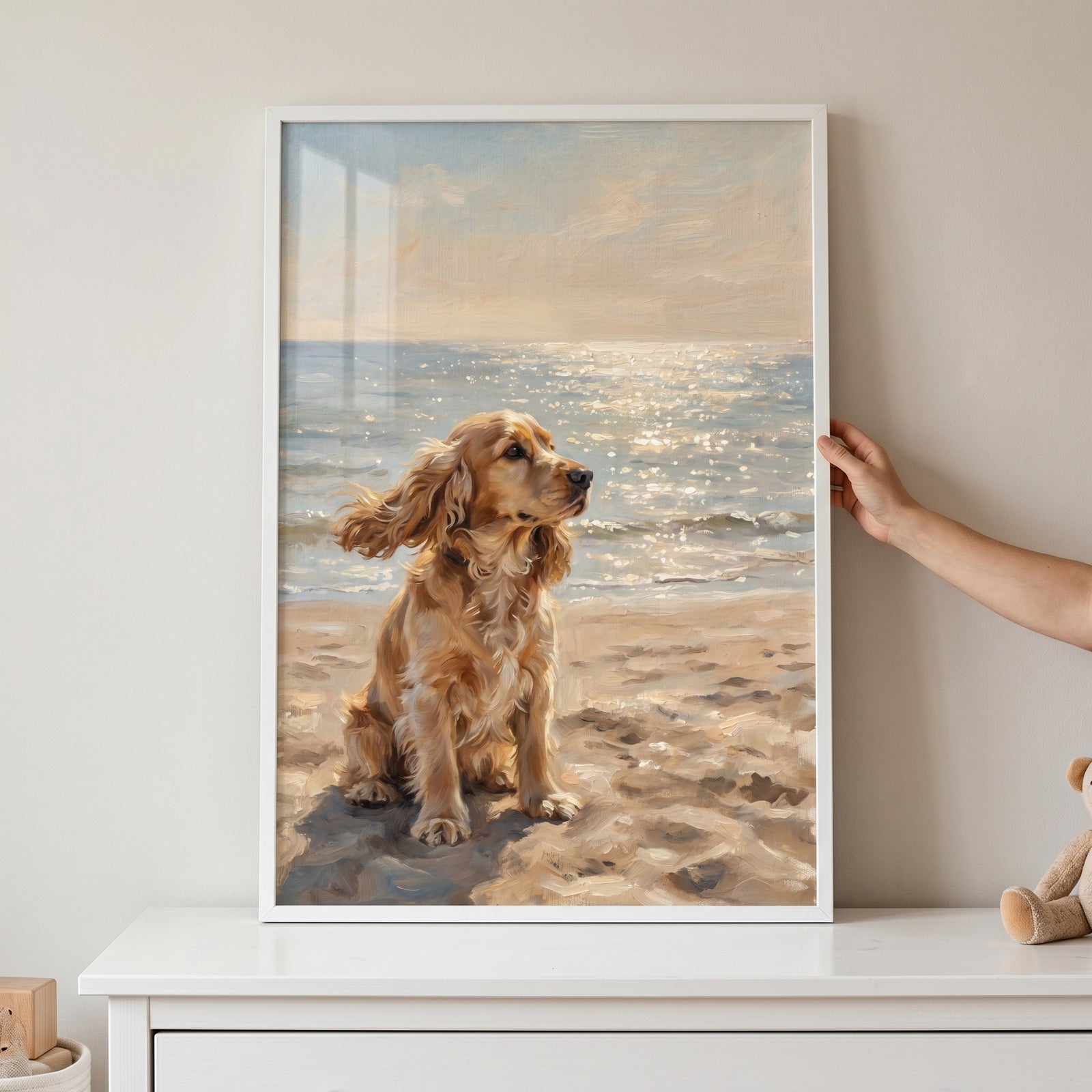 Honey colored cocker spaniel dog artwork in a white frame, showing a pet on a beach looking at the sparkling sea.