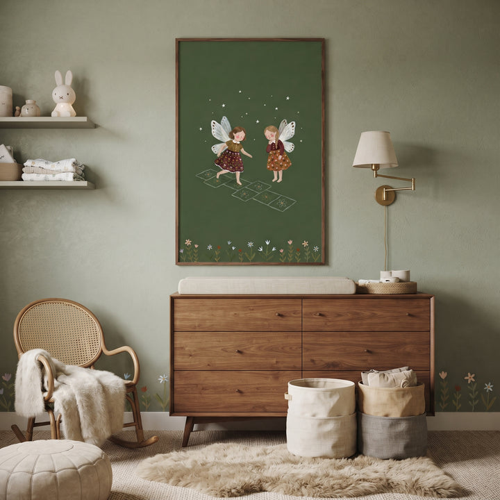 Hopscotch playing garden fairies wall art above a dresser in a sage green nursery with a rocking chair and storage bins.