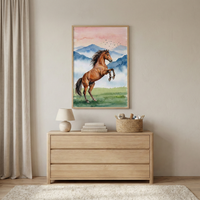 A minimalist room interior featuring a light-toned wooden dresser against a plain wall. Above the dresser hangs a framed watercolor-style artwork depicting a brown horse rearing up on its hind legs in a grassy field. The background of the artwork shows misty blue mountains under a soft pink and orange sky with a flock of birds.