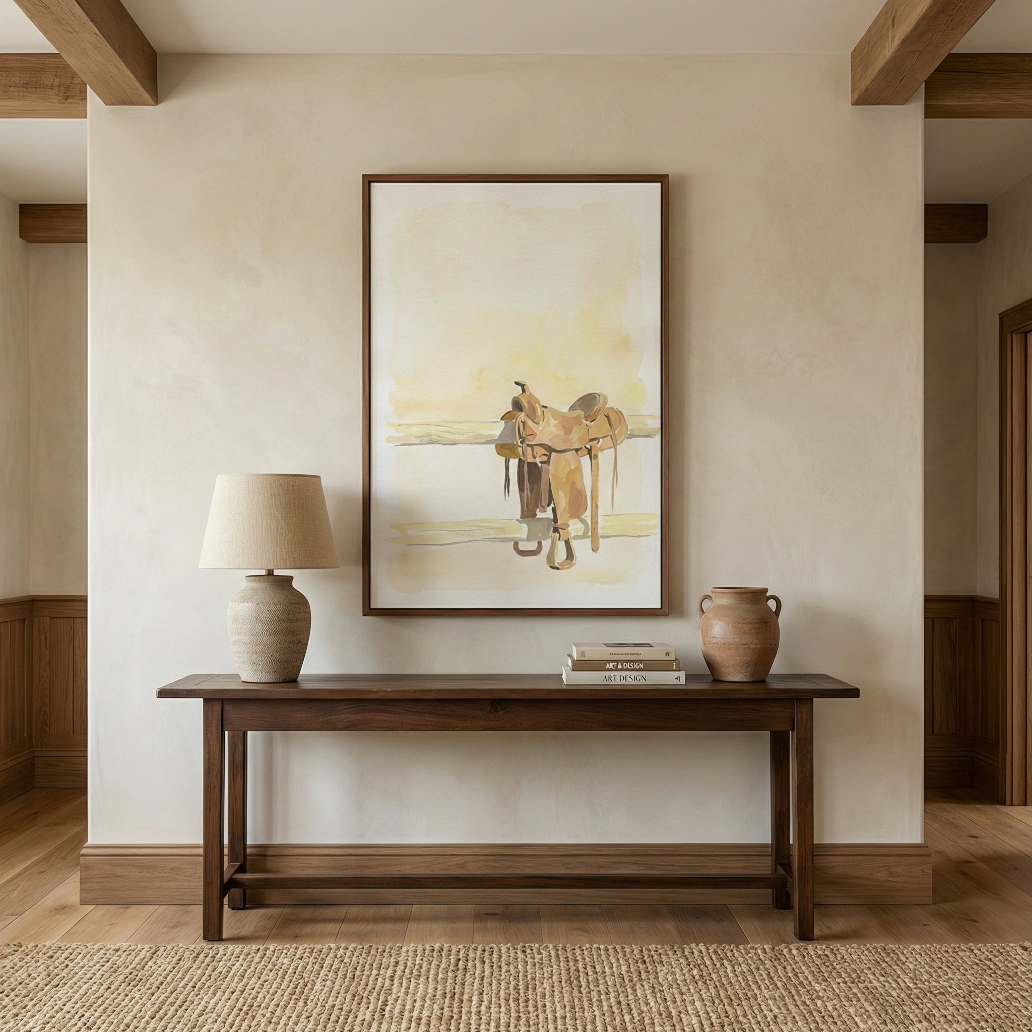 Large western-themed art print featuring a watercolor horse saddle on a fence, displayed in a rustic hallway above a wooden console table. The painting evokes cowboy culture with warm, neutral hues and a quiet, open-range feel.