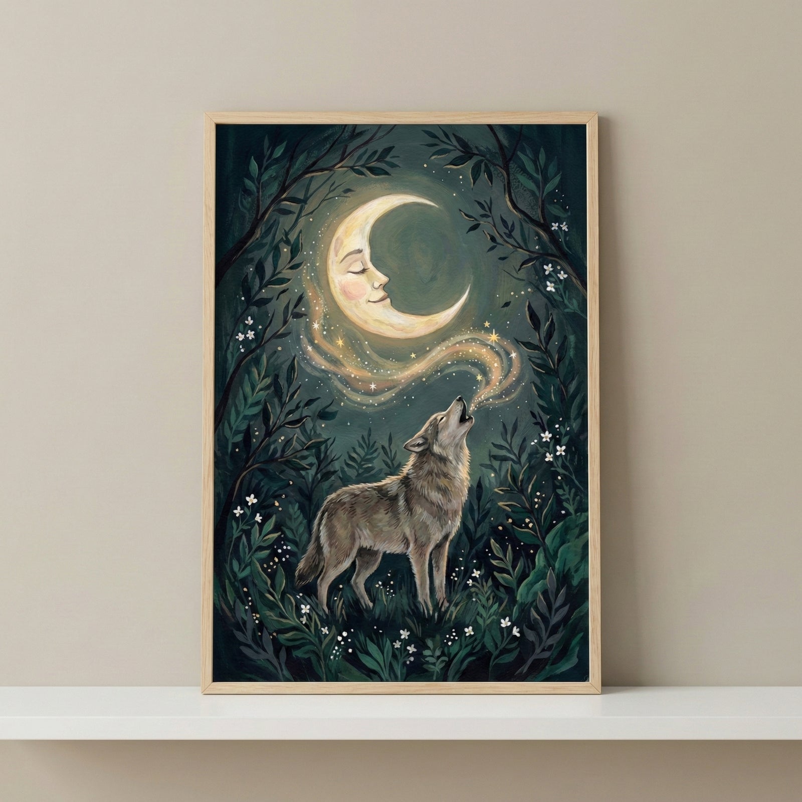 A vertical, wood-framed illustration depicts a wolf in a dark, mystical forest, howling toward a crescent moon that features a peaceful human face. A shimmering trail of golden starlight connects the wolf's howl to the moon. The forest background is filled with layered green foliage and tiny white flowers. The framed piece is displayed on a white shelf against a plain, neutral-toned wall.
