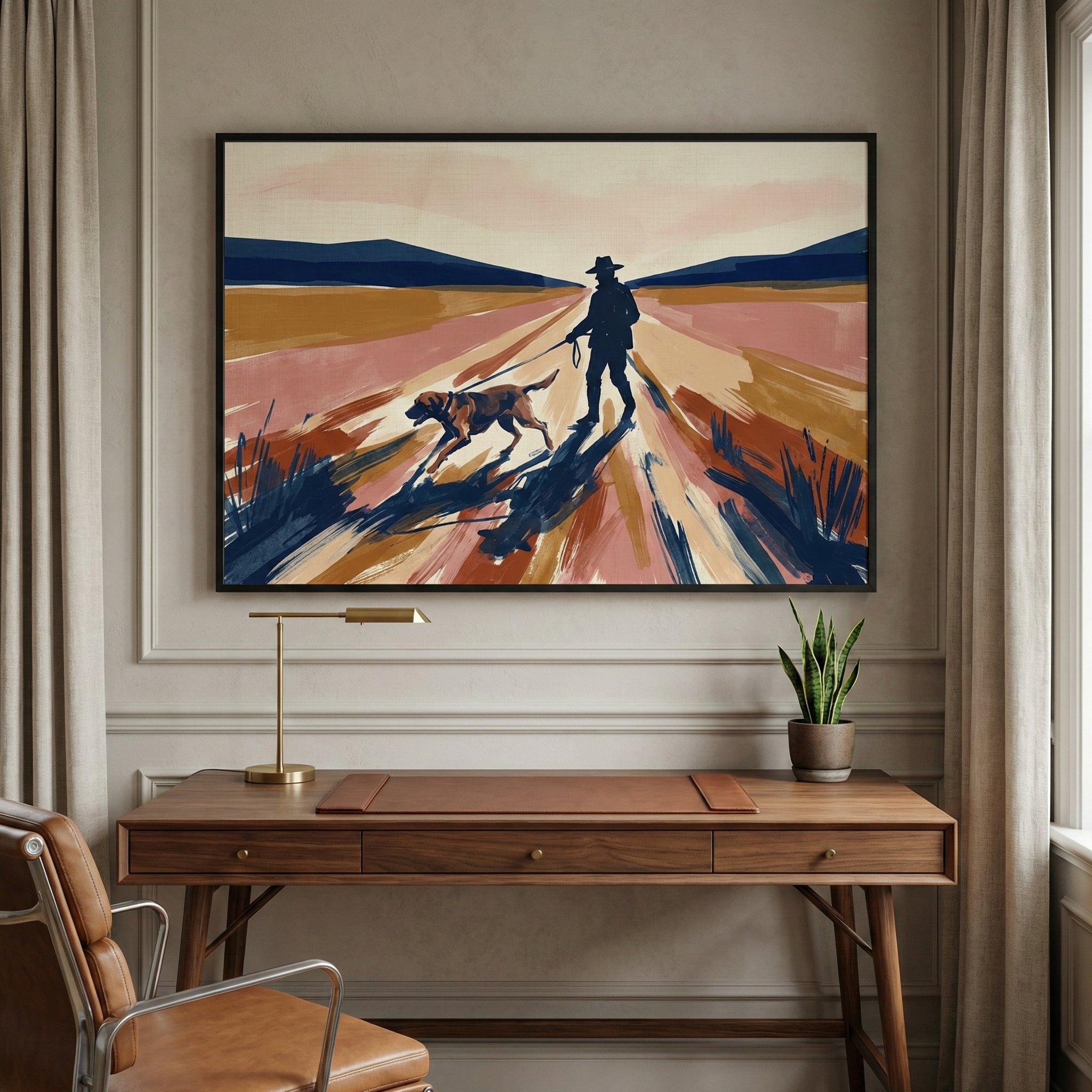 A large, framed art piece hangs on a paneled wall above a wooden desk. The artwork shows a silhouette of a man in a hat walking a dog on a leash down a path in a wide landscape. The style features broad, textured strokes in shades of rust, tan, and dark blue, with long shadows stretching forward. The desk below has a brass lamp and a small plant in a pot. A brown leather chair is in the foreground, and soft curtains frame the side of the room.