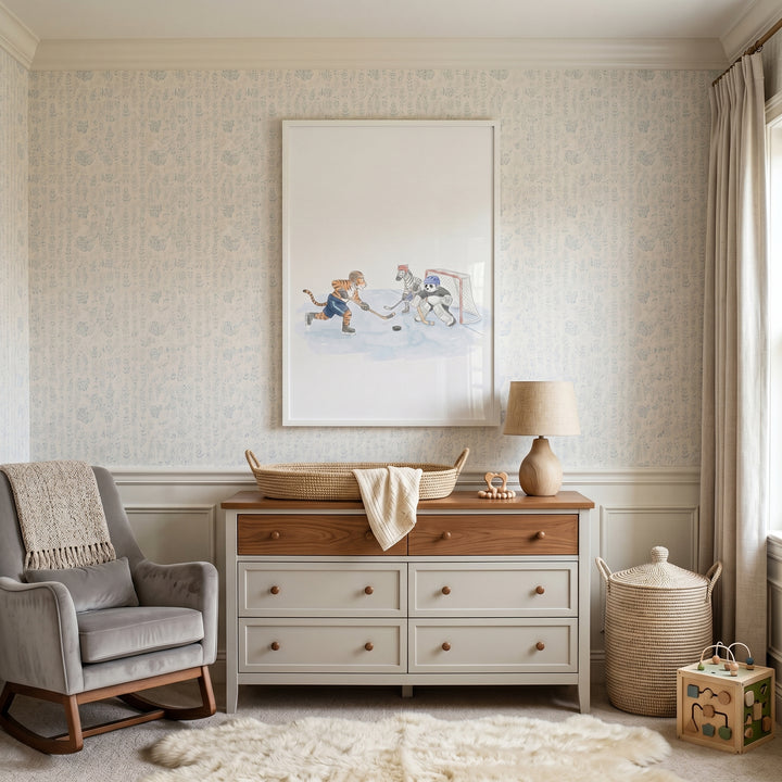A nursery with a gray rocker, two-tone dresser, and ice hockey goalie animals wall art above a woven changing basket.