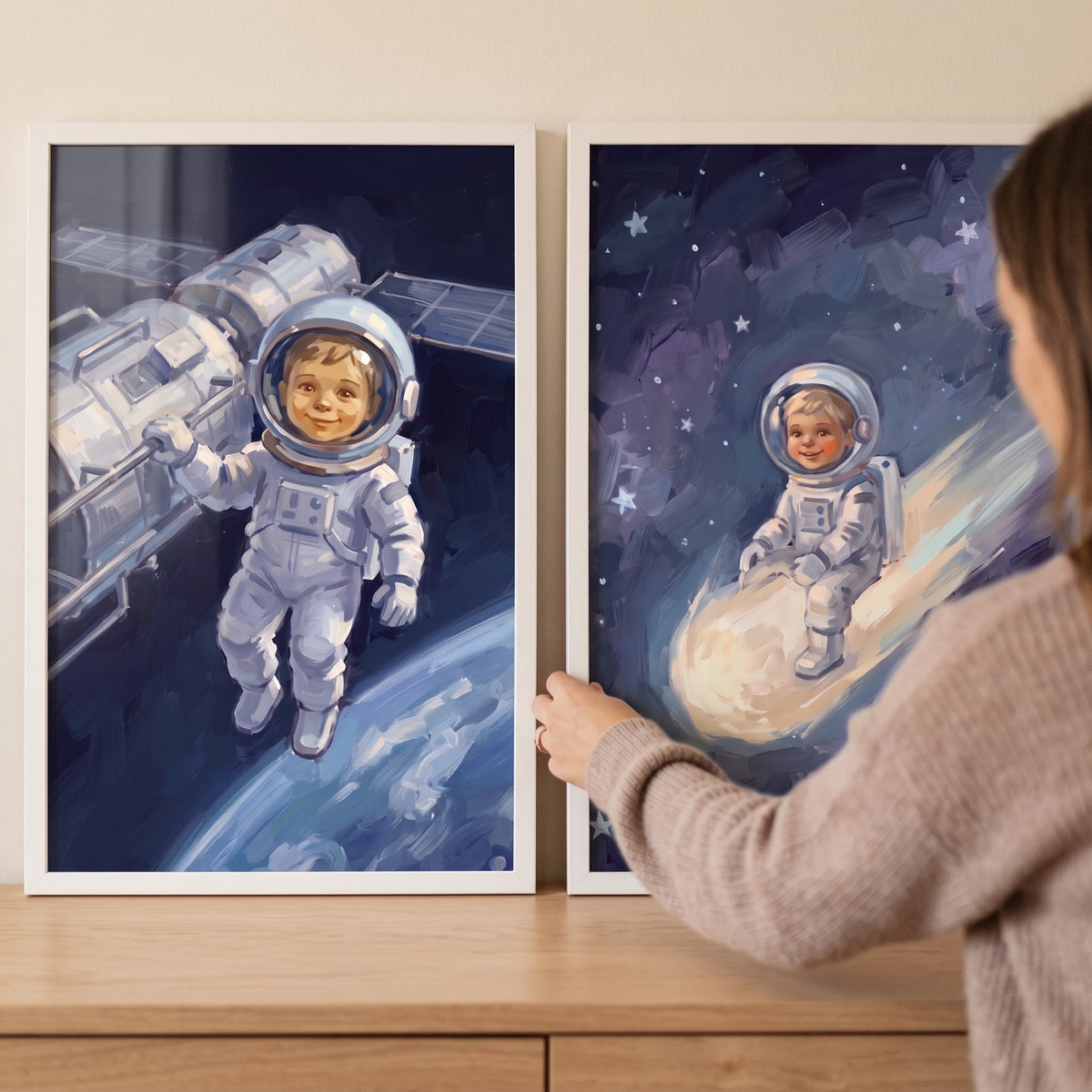 Hands adjusting an impasto navy baby astronaut wall art set of 2 with a child near a satellite and riding a comet.