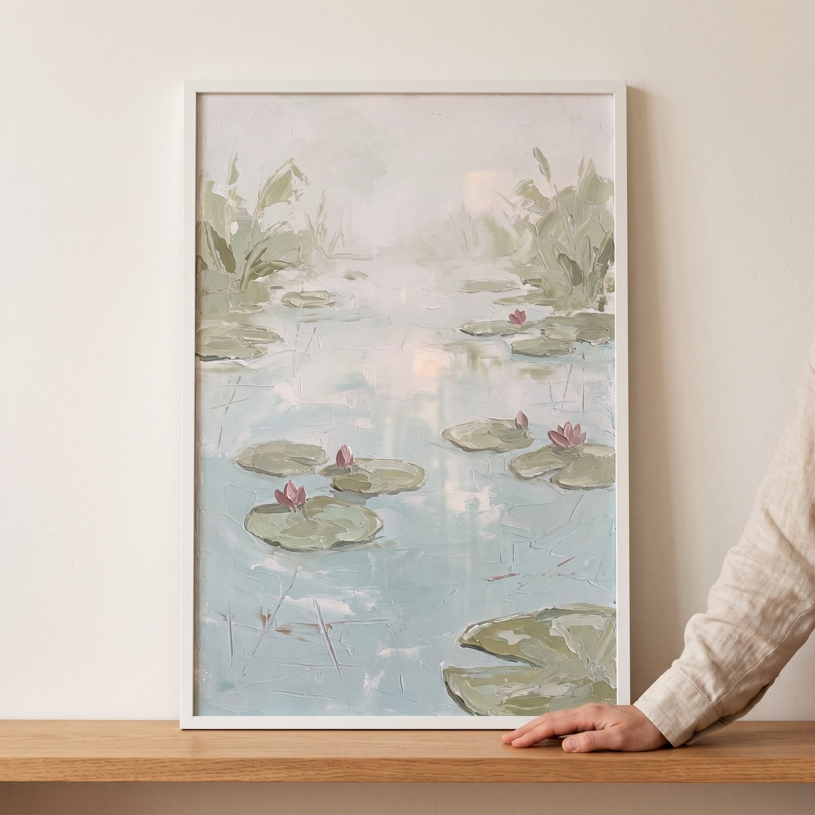 Framed impasto pink water lily pond wall art features textured green pads and pink blossoms on soft blue water.