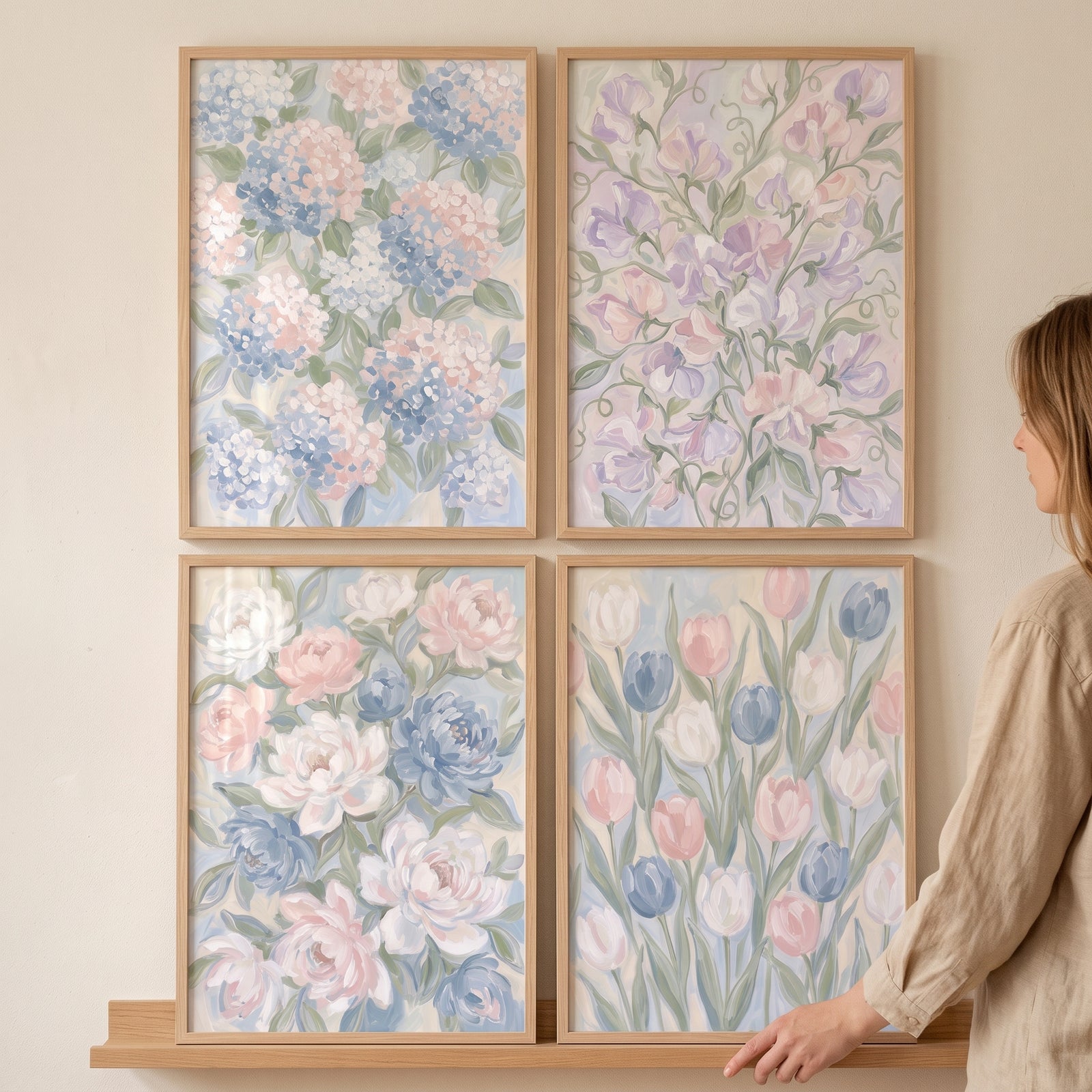 Impressionist blush blue floral artwork set of 4 in light wood frames on a neutral wall next to a woman.