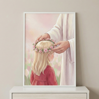 A framed soft-toned illustration depicts Jesus gently placing a pink floral crown on a young girl's head. The girl has long blonde hair and wears a simple red dress. Jesus is shown from the torso down, draped in a white robe. The background is a dreamy, hazy garden with hints of pink and green flowers in a watercolor style. This serene art piece is displayed on a white dresser against a neutral wall, creating a peaceful and spiritual atmosphere.