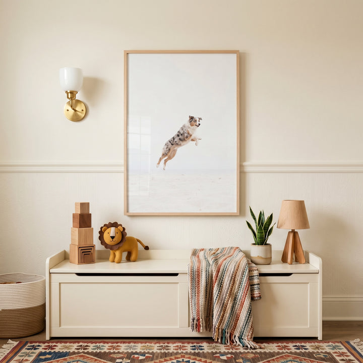 Jumping dog wall art hangs above a storage bench with a toy lion, wooden blocks, and a lamp in a neutral room.