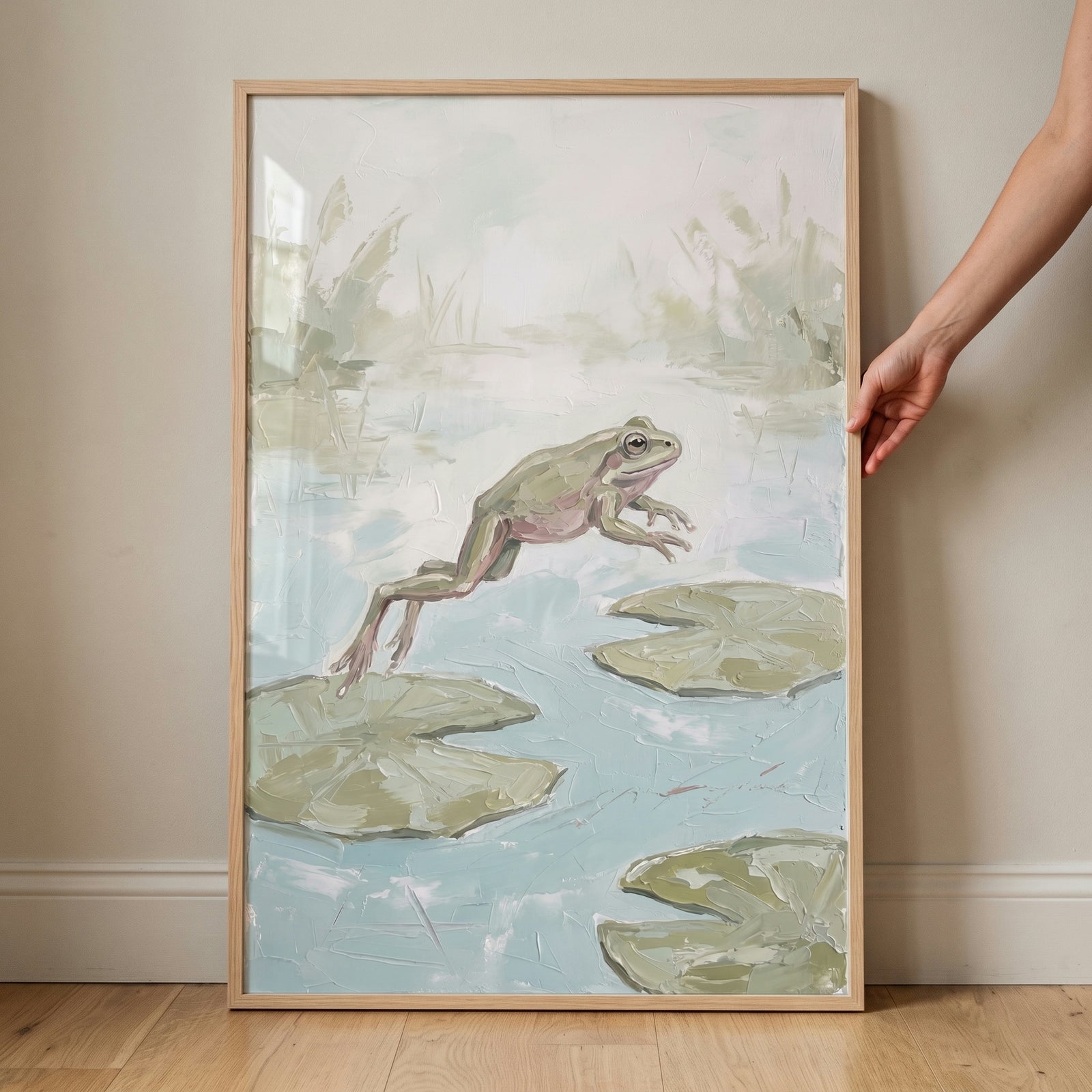 Framed jumping lily pad frog wall art depicts a textured green frog leaping over lily pads in a soft, misty pond.