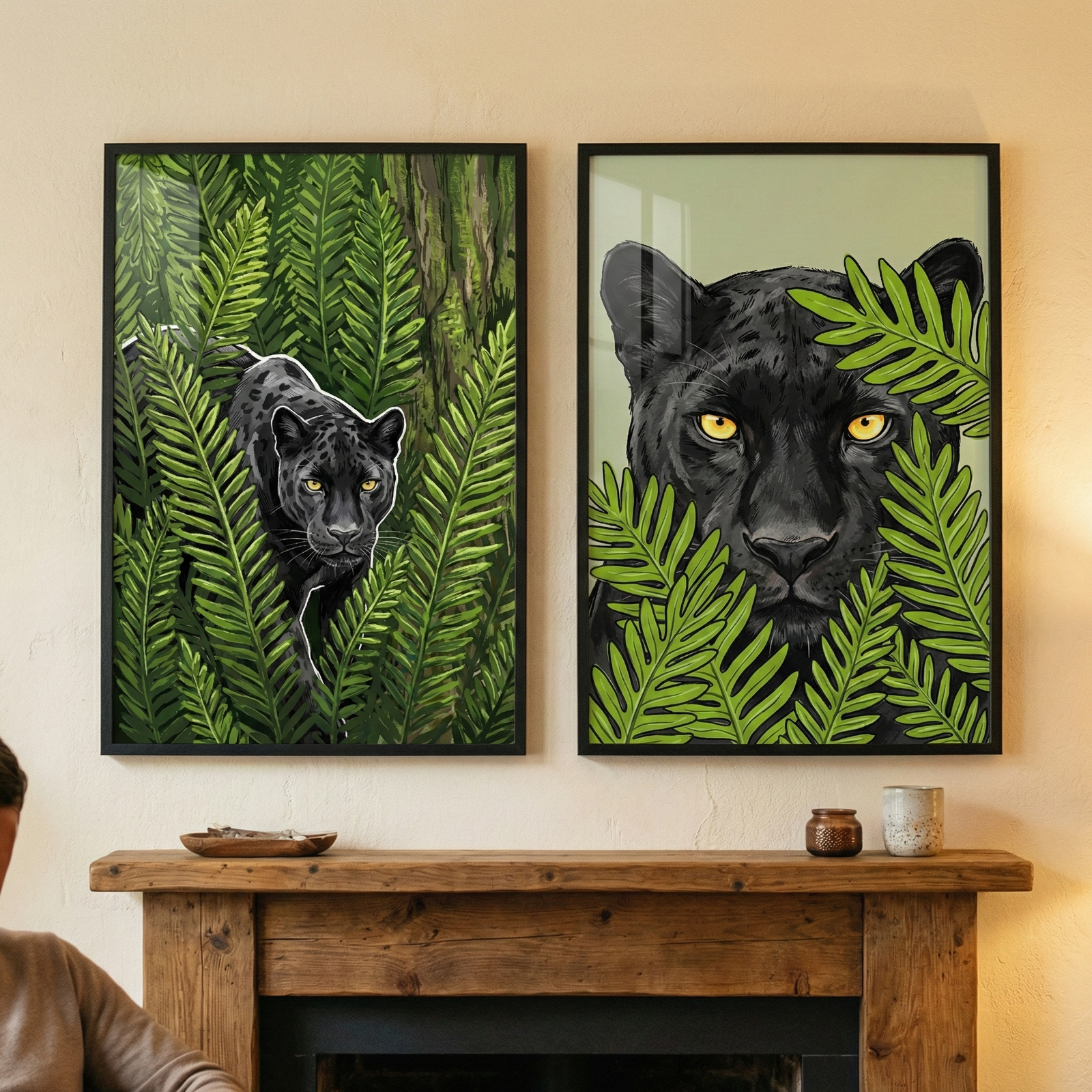 Two vertical framed illustrations featuring black panthers hang side-by-side on a light-colored wall. The illustration on the left shows a sleek black panther with a thin white outline moving through a dense patch of green ferns. The illustration on the right is a close-up of a panther's face with piercing yellow eyes, partially obscured by large, vibrant green leaves. The frames are placed above a rustic wooden fireplace mantle adorned with small decorative containers.