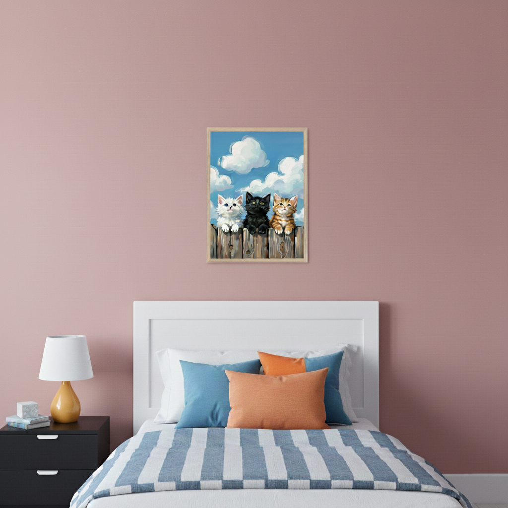 Modern bedroom with a white bed, black nightstand, and lamp. A framed illustration of three kittens (white, black, tabby) on a wooden fence under a cloudy sky hangs above the bed.