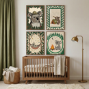 A wooden crib sits against a white nursery wall beneath four framed koala prints arranged in a grid. The artwork shows playful camping themed koalas with a safari hat, telescope and tent marked "01", hammock under stars, and campfire scene, adding a cozy woodland feel to the room.