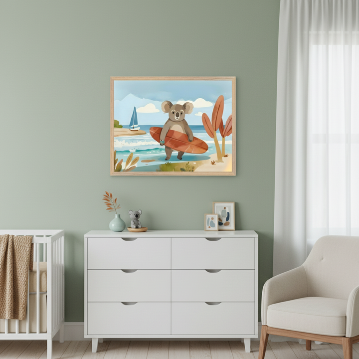 Modern nursery with a white crib, white dresser, and beige armchair. A framed watercolor illustration of a surfing koala on a beach with a sailboat hangs above the dresser.