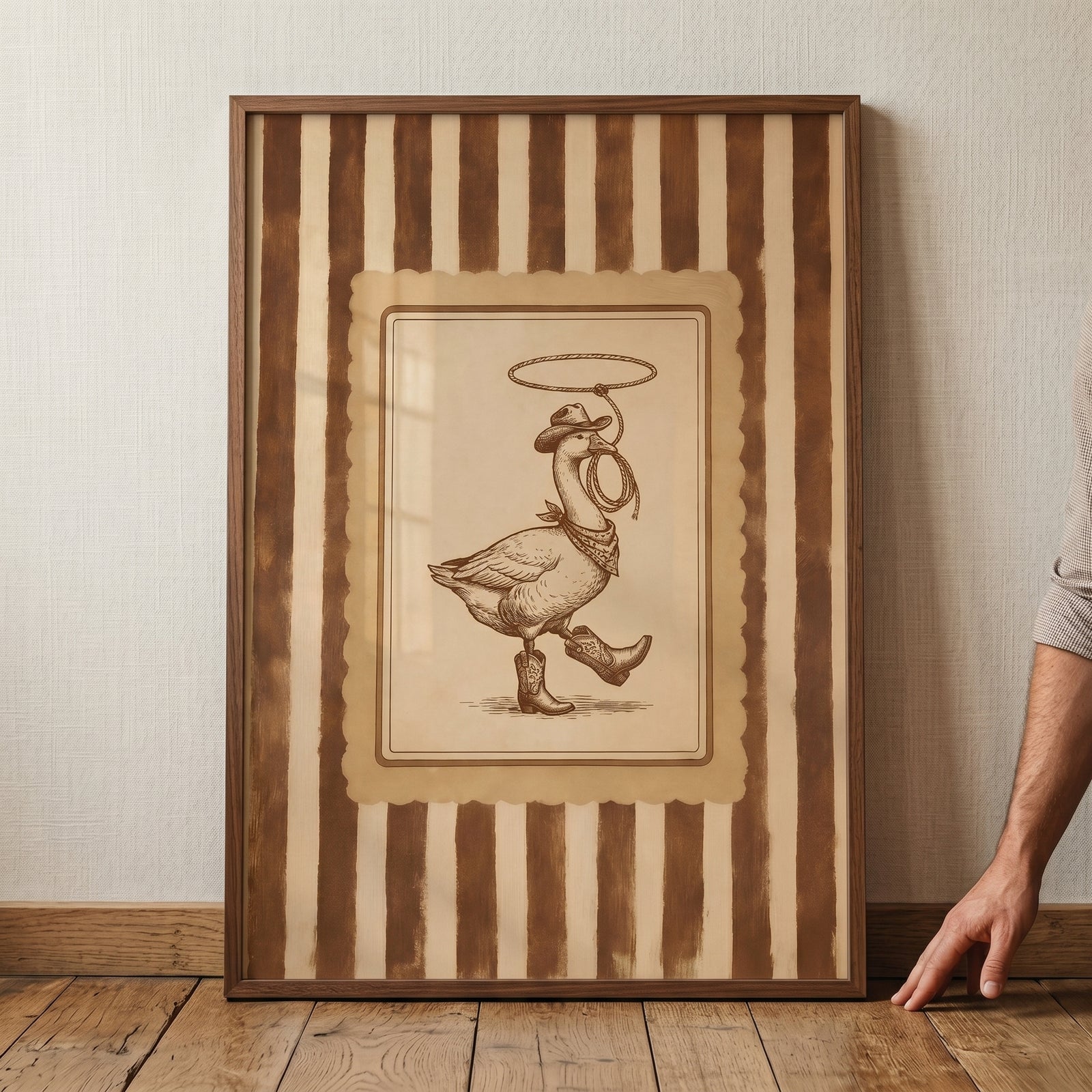 Lasso spinning cowboy goose wall art depicts a goose in a western hat and boots within a brown striped frame.