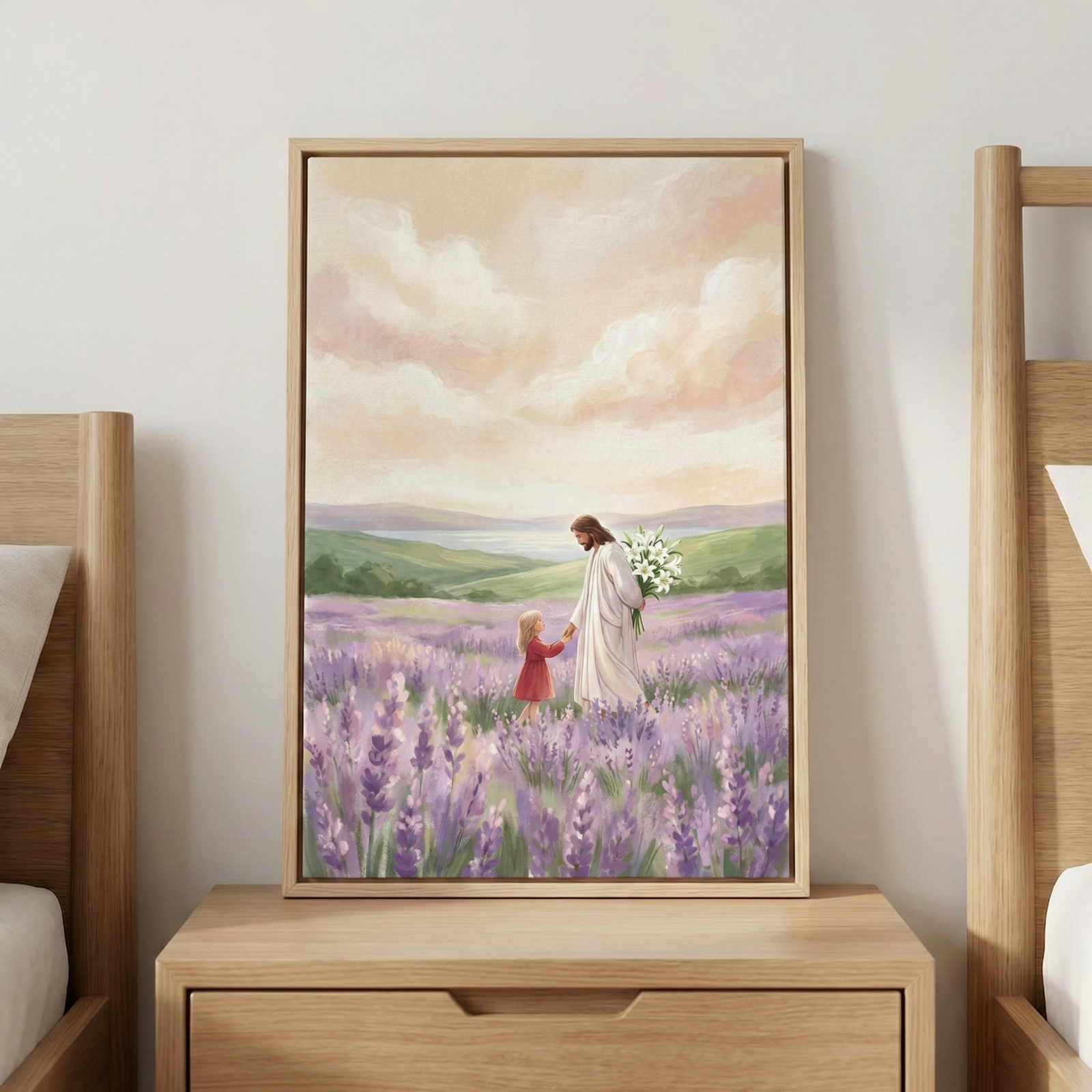 A framed vertical artwork sits on a wooden nightstand between two bed frames. The illustration depicts Jesus in a white robe, holding white lilies and walking through a lavender field with a young girl in a red dress. They hold hands as they stroll through the purple flowers. In the background, green hills lead to a calm body of water under a sky with soft pink and orange clouds. The image features soft, textured brushwork and a peaceful, serene atmosphere.