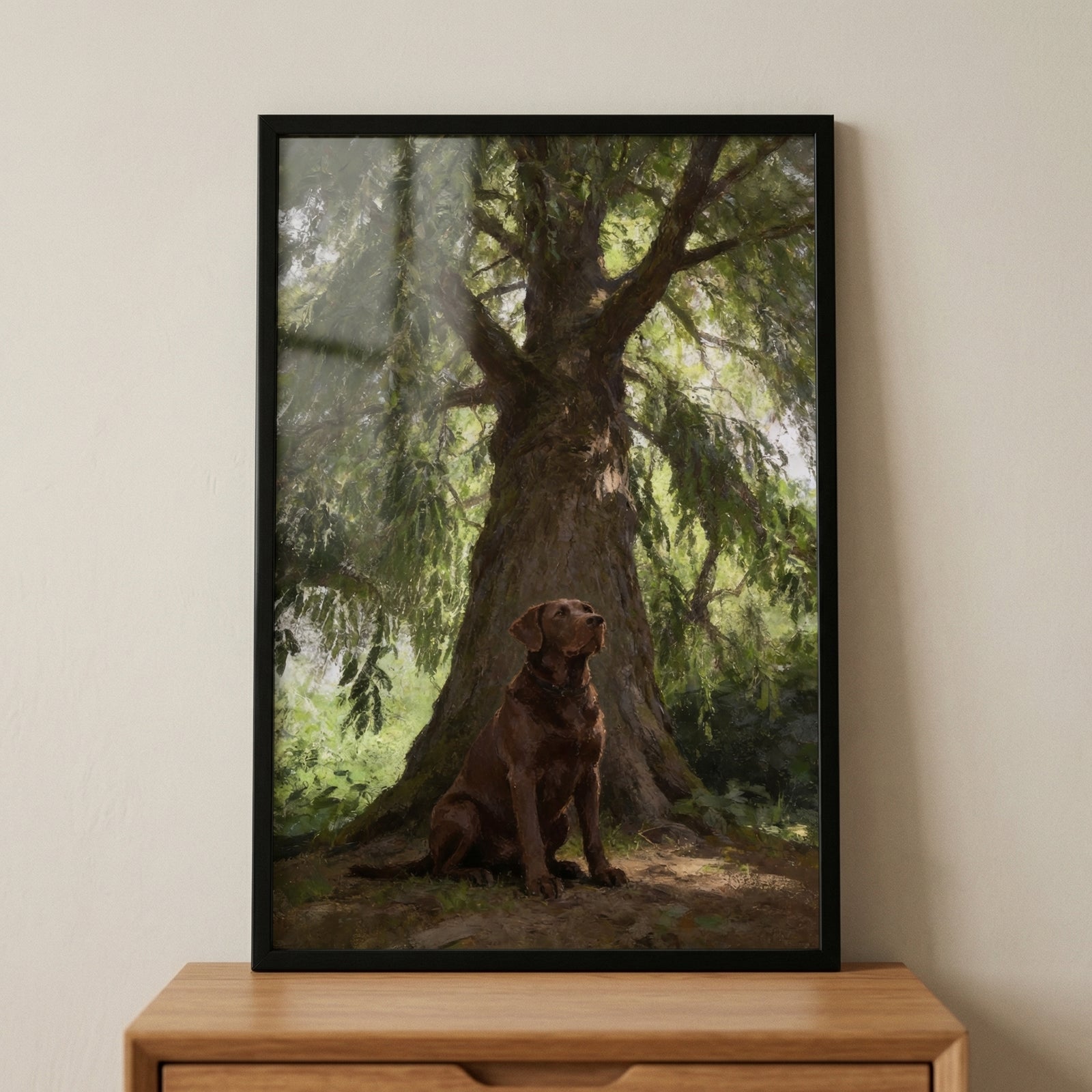 Framed painting of a chocolate labrador sitting at the base of a large tree with sunlight filtering through green leaves above. The warm earthy tones and soft light create a peaceful woodland scene that adds a calming natural focal point to the room.