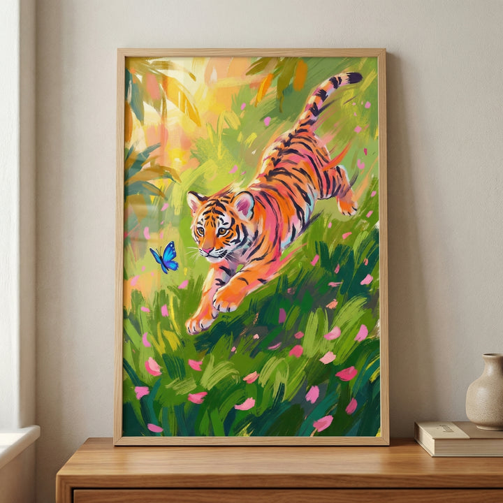 A framed digital illustration features a lively tiger cub leaping through a dense field of green grass and scattered pink petals. The cub's orange fur and black stripes are rendered with expressive, visible strokes that convey a sense of motion and energy. A small, bright blue butterfly flutters in the air just ahead of the cub. 
