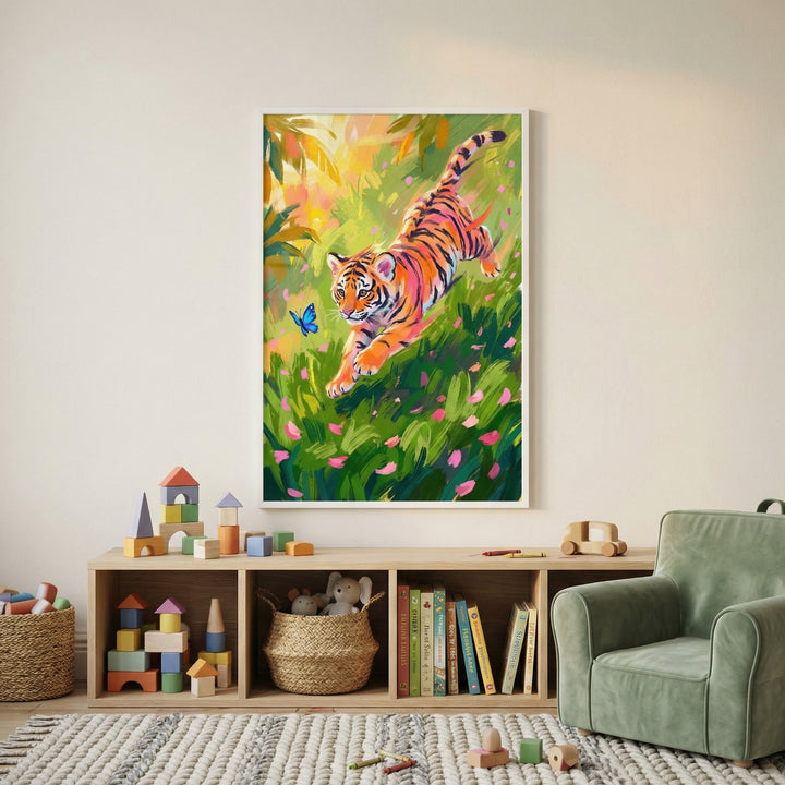 A bright and airy child's playroom featuring a large, framed impressionistic oil-style illustration as a focal point on a plain white wall. The artwork captures a playful young tiger cub in mid-leap through a dense, lush green meadow filled with falling pink and yellow flower petals. A small, bright blue butterfly flutters just in front of the cub's face. 