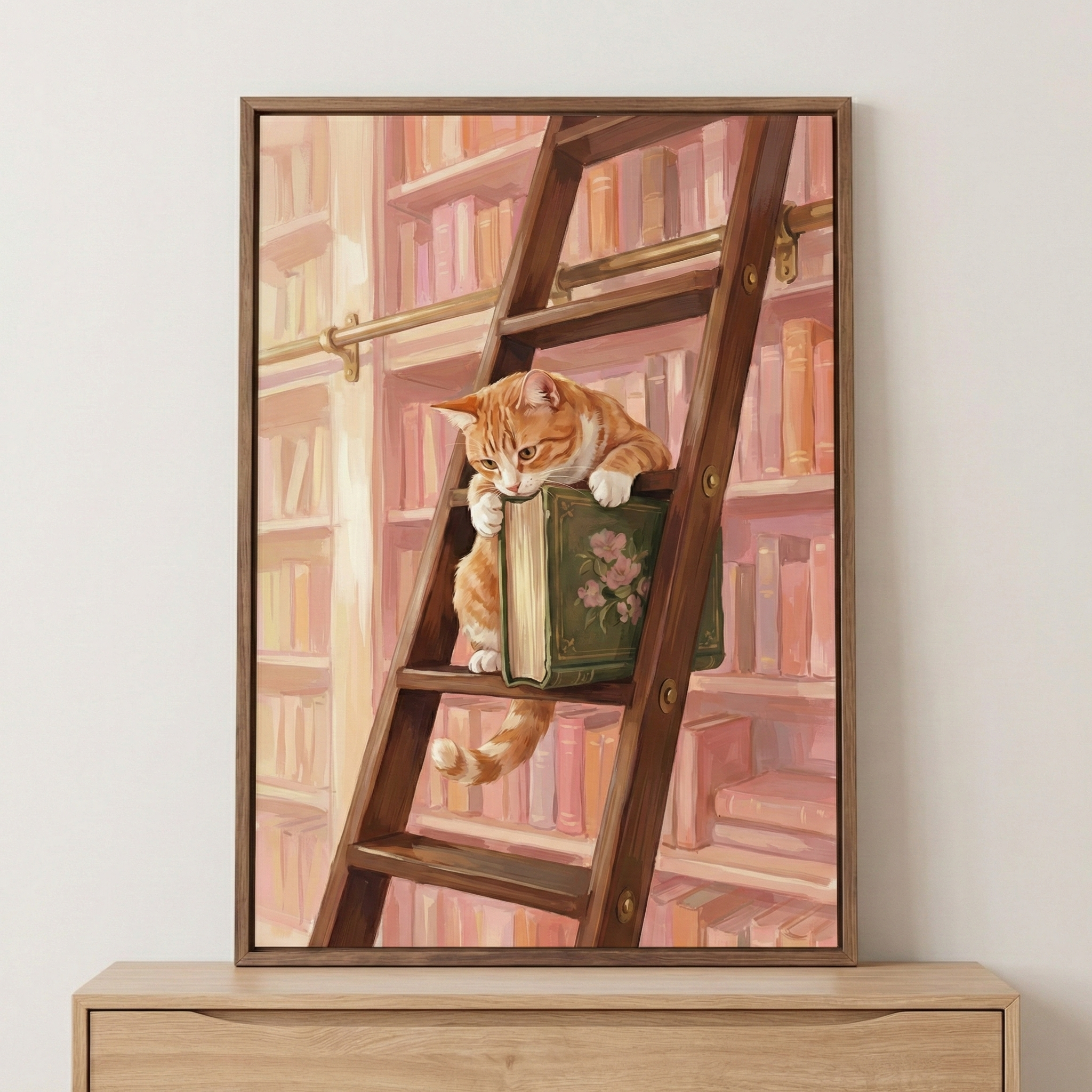 A vertical framed artwork depicts an orange and white tabby cat on a dark wooden library ladder. The cat is perched on a rung, leaning its chest and front paws against a thick green book with a pink flower design on its cover. The cat's tail hangs loosely down between the ladder rungs. In the background, tall shelves are packed with books in soft shades of pink, cream, and peach. A metal rail for the ladder runs horizontally across the shelves. 