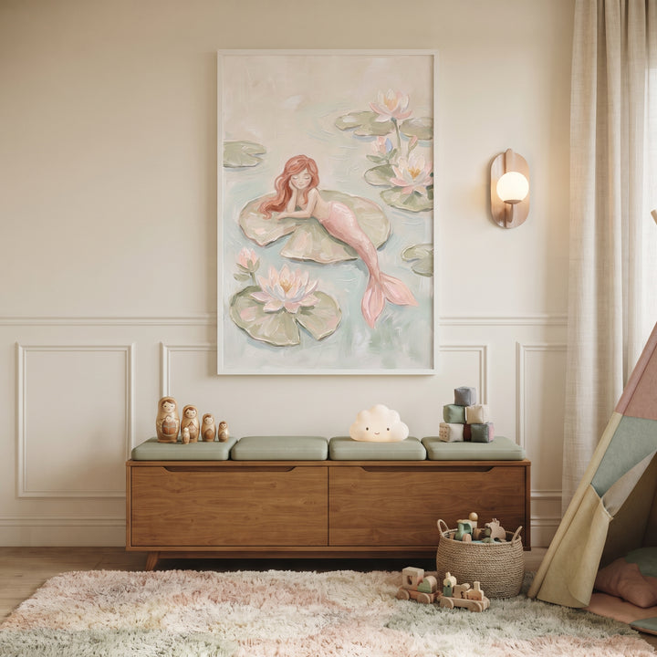 Lily pad pink mermaid wall art hangs above a wooden storage bench and plush rug in a cozy, neutral nursery.