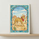 Whimsical illustration of a lion dressed as a cowboy, wearing a red bandana and a tan hat with a red star, walking through a desert landscape with cacti and mesas under a blue sky. The scene is framed with a scalloped blue border decorated with yellow stars.