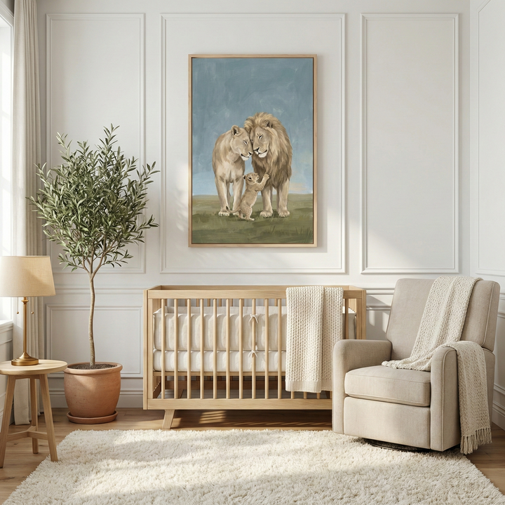 A serene nursery scene is depicted with elegant white paneled walls and a plush white shag rug. Centered against the wall is a light-toned wooden crib, fitted with a soft white bumper and a cream-colored knit blanket draped over its side. Above the crib hangs a large, vertically oriented framed artwork that shows a family of lions—a male with a full mane, a female, and a small cub—standing together in a grassy field beneath a soft blue sky. 