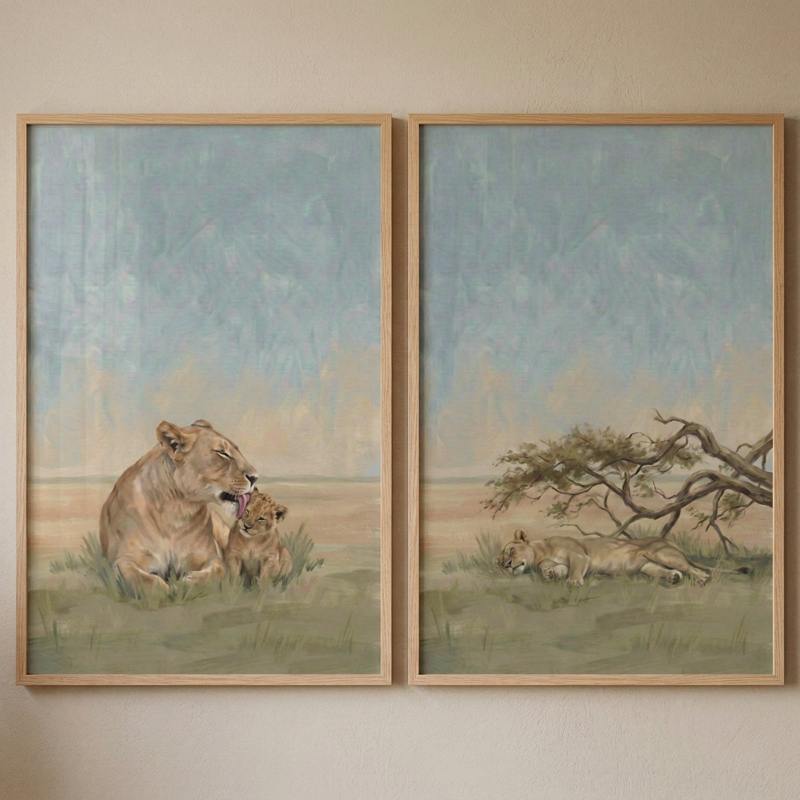 Two framed wildlife paintings show quiet moments between lions in a soft savanna landscape. One artwork shows a lioness gently grooming her cub while they sit together in tall grass. The second shows a lioness sleeping peacefully beneath a low spreading tree in the open grassland.