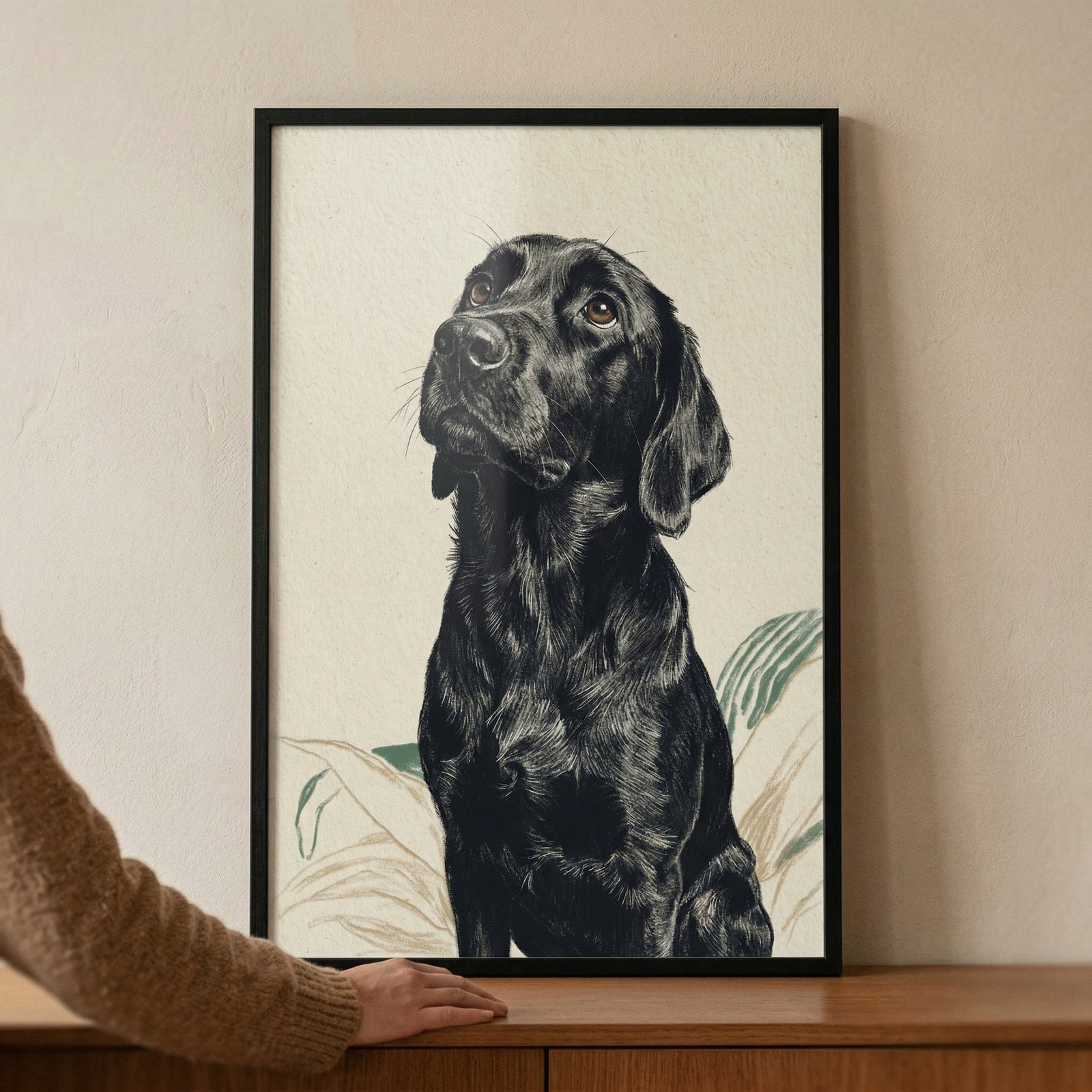 A framed piece of wall art featuring a detailed illustration of a black dog. The dog is depicted in a three-quarter view, looking upwards with a soulful expression. The style of the artwork is characterized by fine, detailed line work that defines the dog's fur and features. 