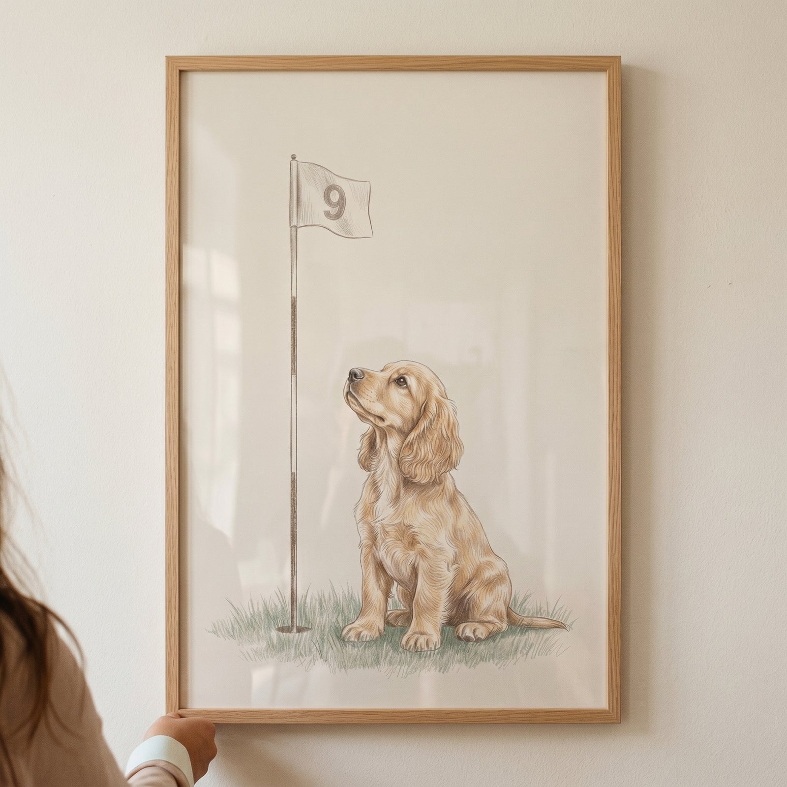 Looking up cocker spaniel dog wall art shows a puppy on grass beside a golf flag numbered nine in a light wood frame.
