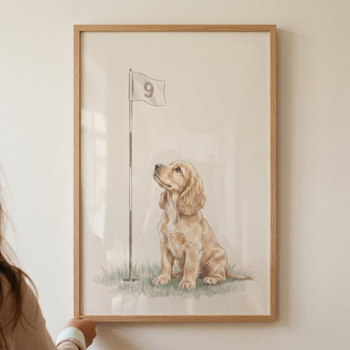 Looking up cocker spaniel dog wall art shows a puppy on grass beside a golf flag numbered nine in a light wood frame.