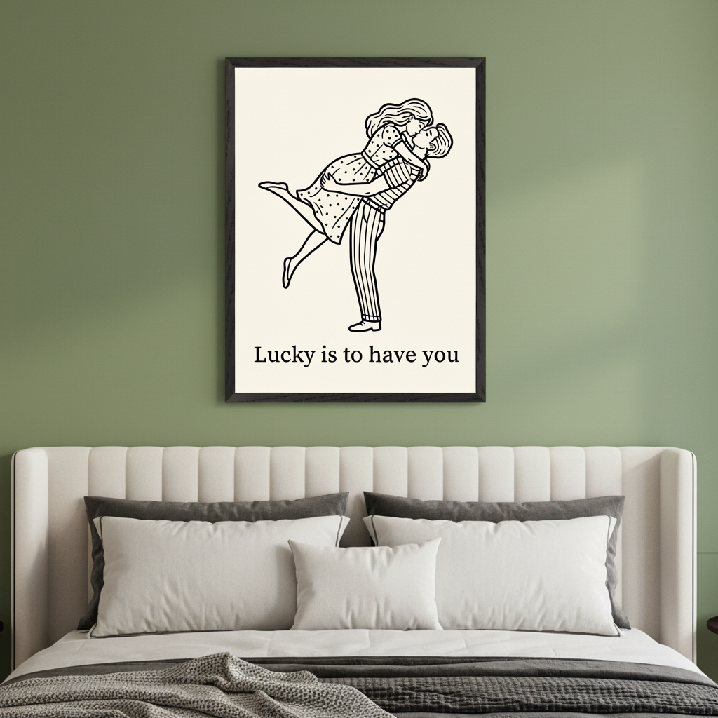 Modern bedroom with a white upholstered bed. A black-framed print featuring a black-and-white line drawing of a man holding and kissing a woman, with "Lucky is to have you" text, hangs centered above the bed on a green wall.