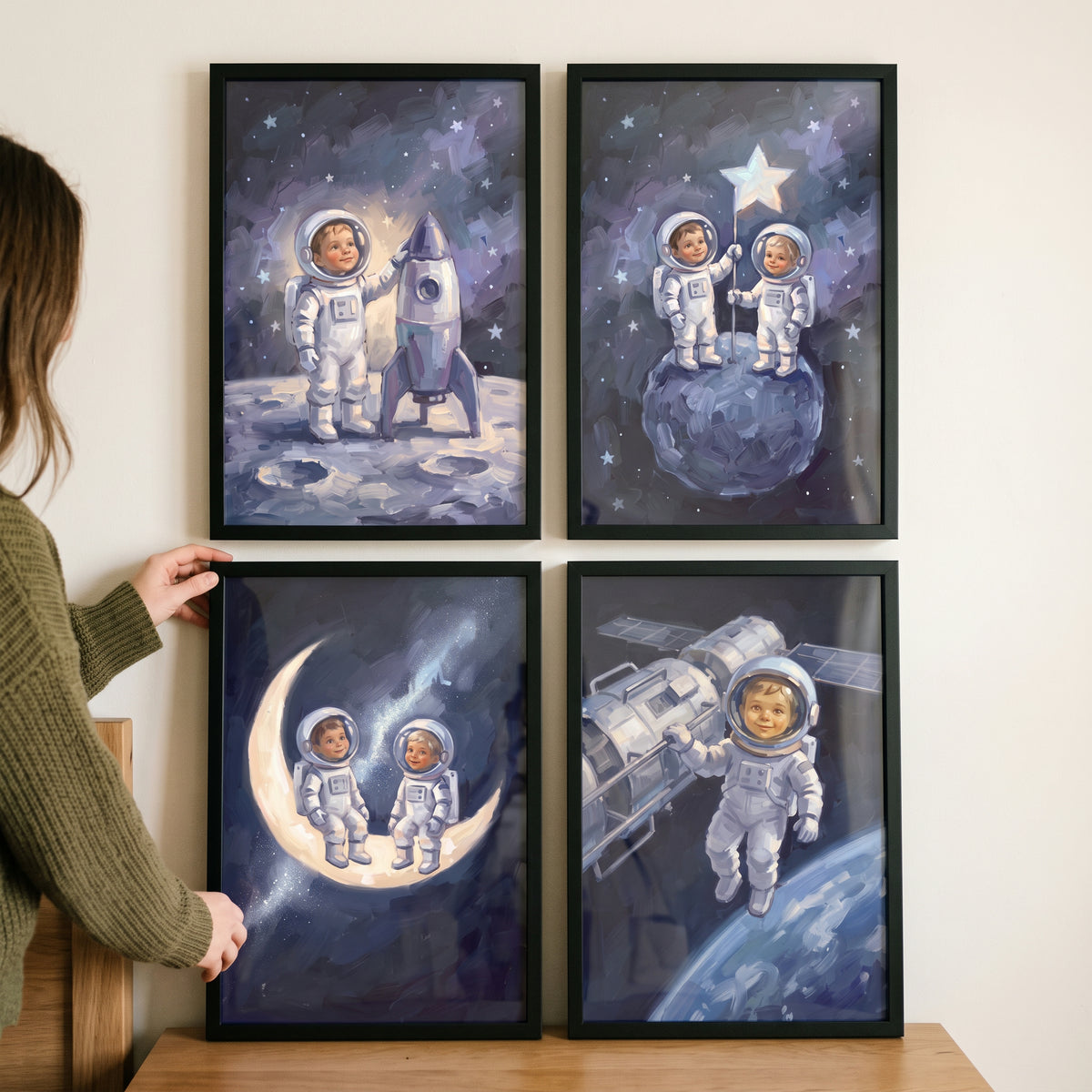 A woman hangs a luminous orbital baby astronaut wall art set of 4 featuring kids in space suits inside black frames.