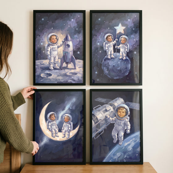 A woman hangs a luminous orbital baby astronaut wall art set of 4 featuring kids in space suits inside black frames.
